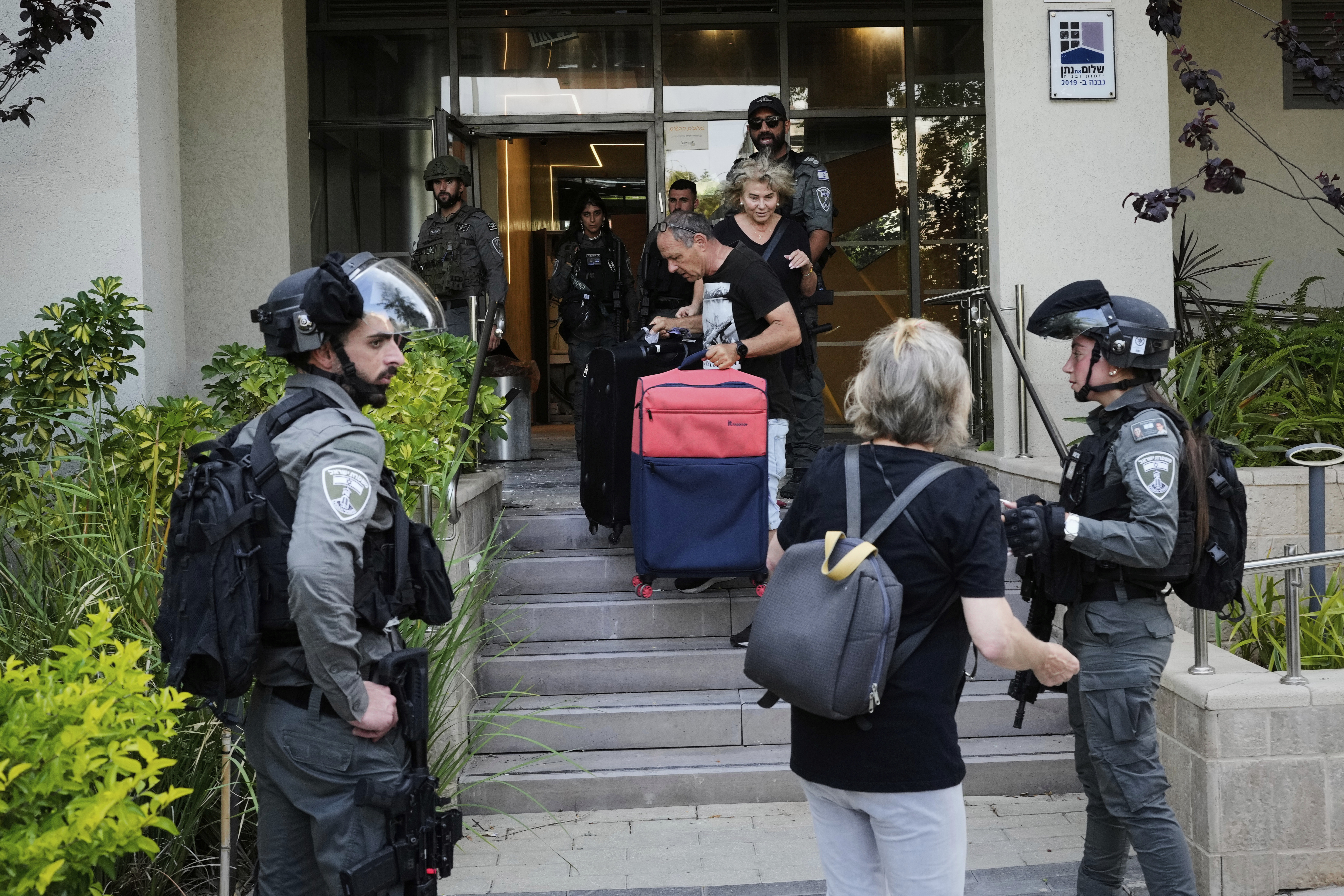 Israeli border police officers help residents to evacuate from a building damaged in an Iranian missile strike in Tel Aviv, Israel, Sunday, June 22, 2025. (AP Photo/Bernat Armangue)