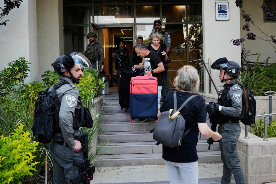 Israeli border police officers help residents to evacuate from a building damaged in an Iranian missile strike in Tel Aviv, Israel, Sunday, June 22, 2025. (AP Photo/Bernat Armangue)