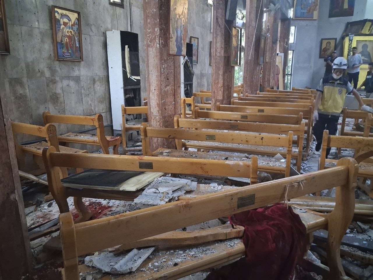 In this photo released by the Syrian official news agency SANA, a Civil Defence worker inspects the damage inside Mar Elias church where a suicide bomber detonated himself in Dweil'a in the outskirts of Damascus, Syria, Sunday June 22, 2025. (SANA via AP)
