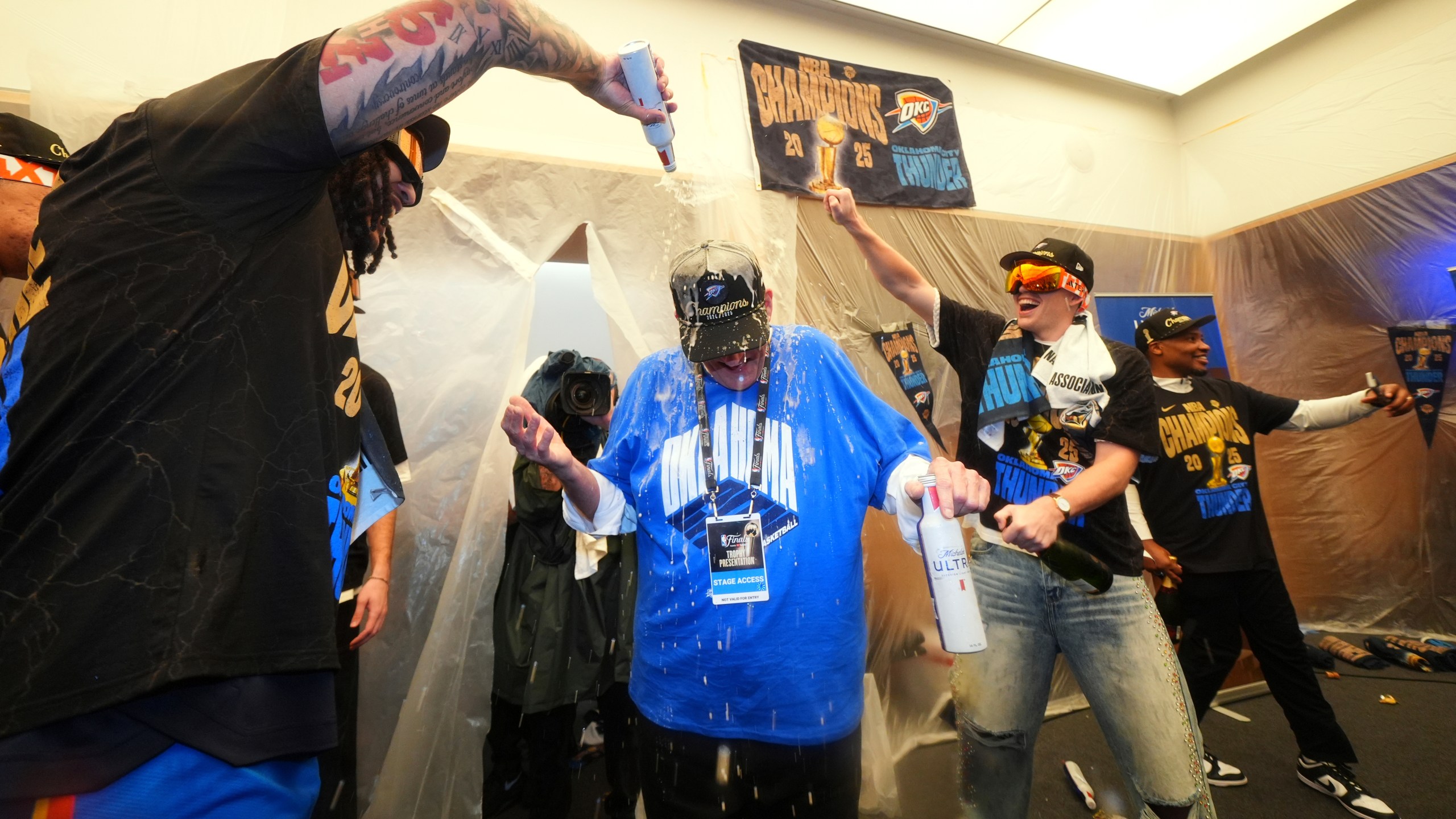 Clay Bennett, center, chairman the ownership group of the Oklahoma City Thunder, celebrates with players in the locker room after winning the NBA basketball championship with a Game 7 victory against the Indiana Pacers Sunday, June 22, 2025, in Oklahoma City. (AP Photo/Julio Cortez)