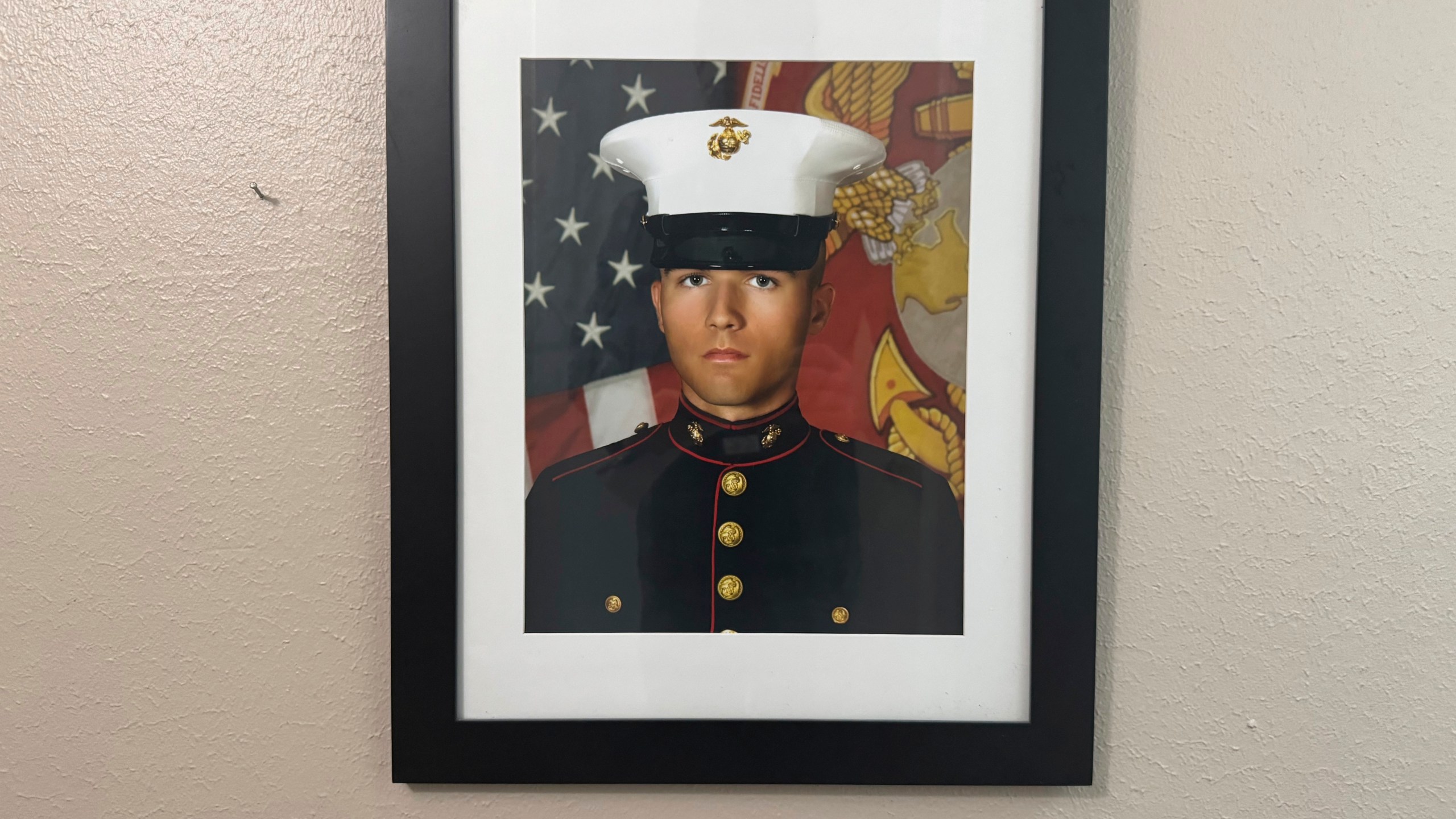 A portrait of Adrian Clouatre during his years of service with the U.S. Marine Corps hangs on the wall of his family's home in Baton Rouge on Tuesday, June 17, 2025. (AP Photo/Jack Brook)