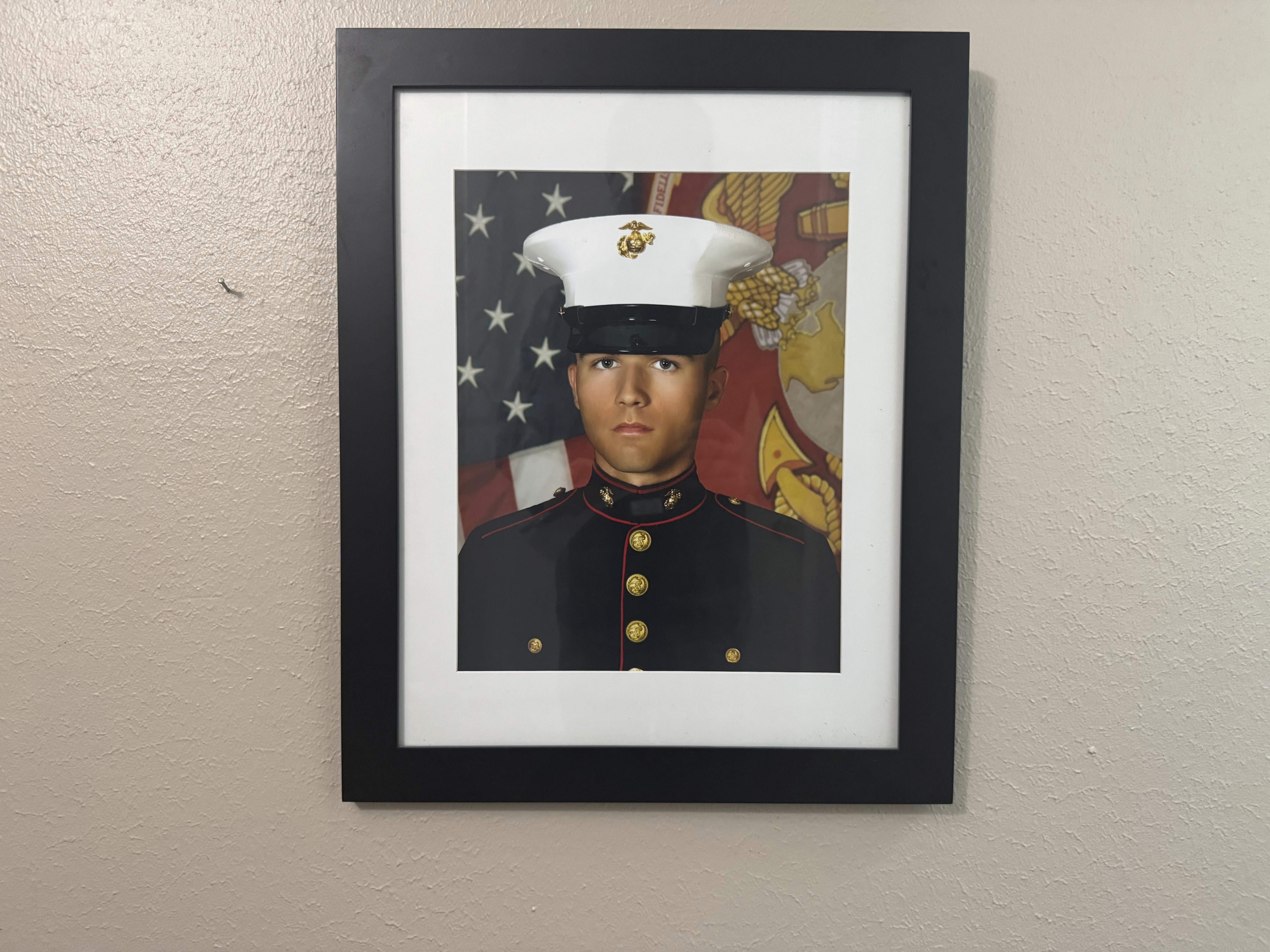 A portrait of Adrian Clouatre during his years of service with the U.S. Marine Corps hangs on the wall of his family's home in Baton Rouge on Tuesday, June 17, 2025. (AP Photo/Jack Brook)