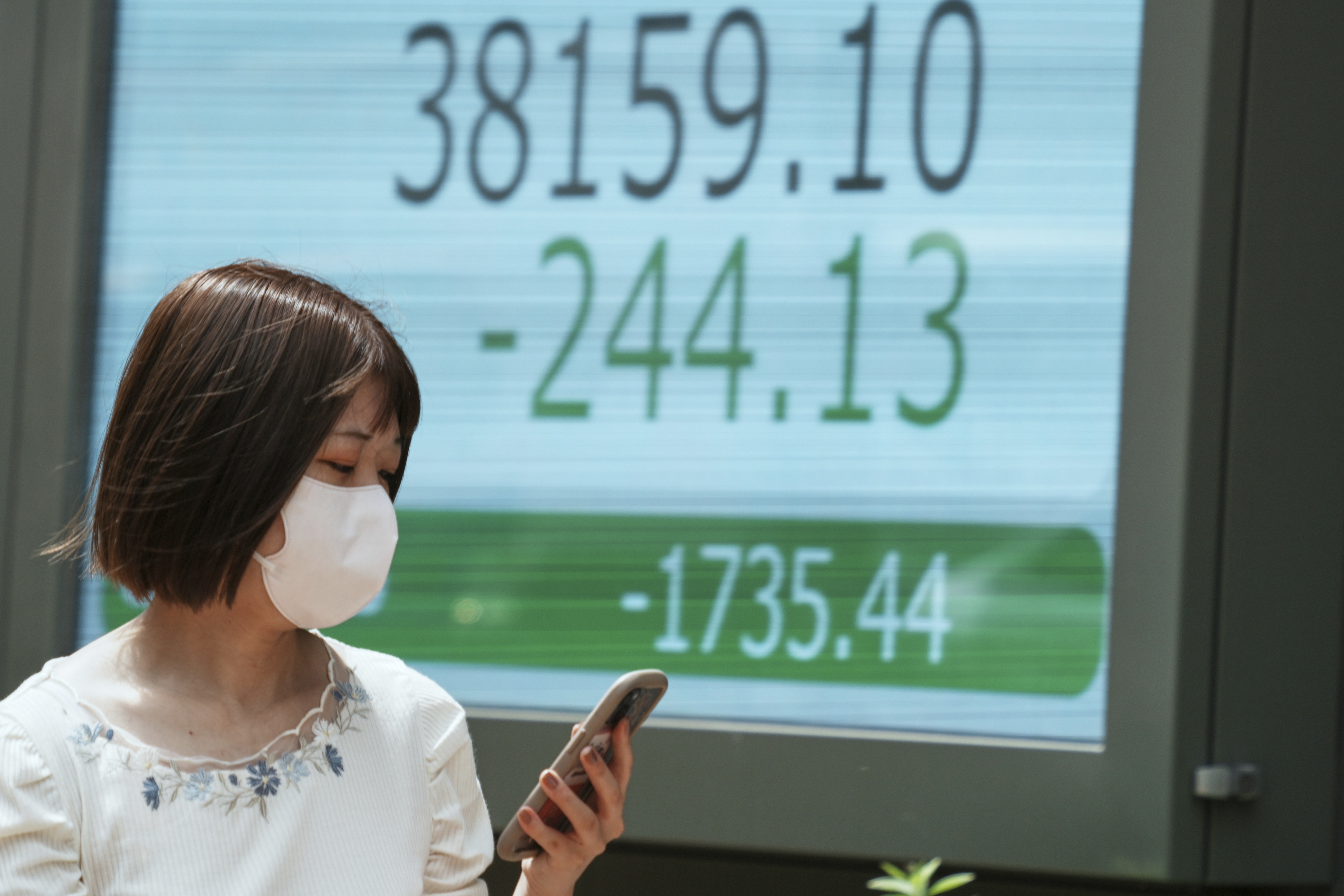 A person walks in front of an electronic stock board showing Japan's Nikkei index at a securities firm Monday, June 23, 2025, in Tokyo. (AP Photo/Eugene Hoshiko)