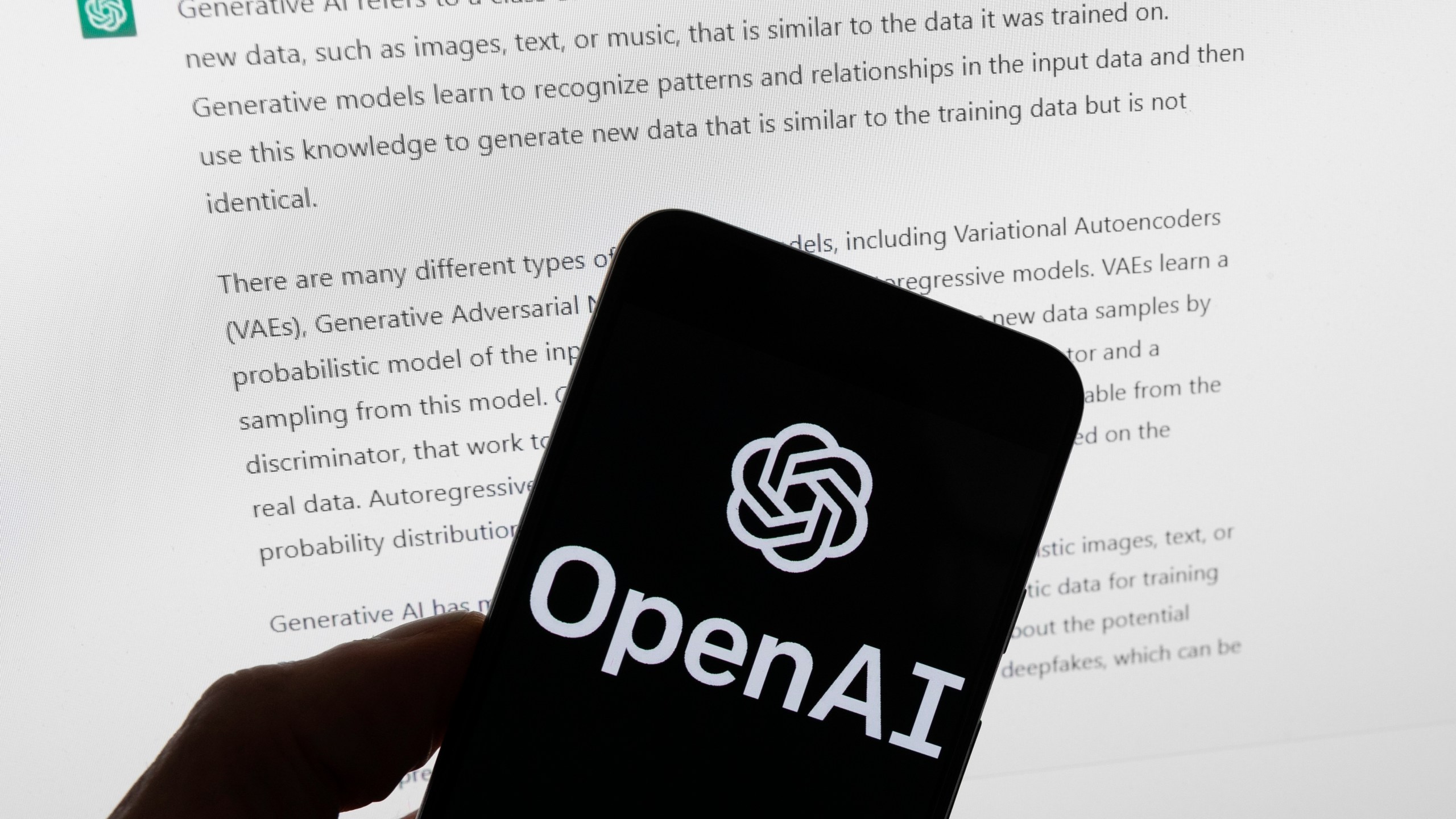 FILE - The OpenAI logo is seen on a mobile phone in front of a computer screen displaying output from ChatGPT, March 21, 2023, in Boston. (AP Photo/Michael Dwyer, File)