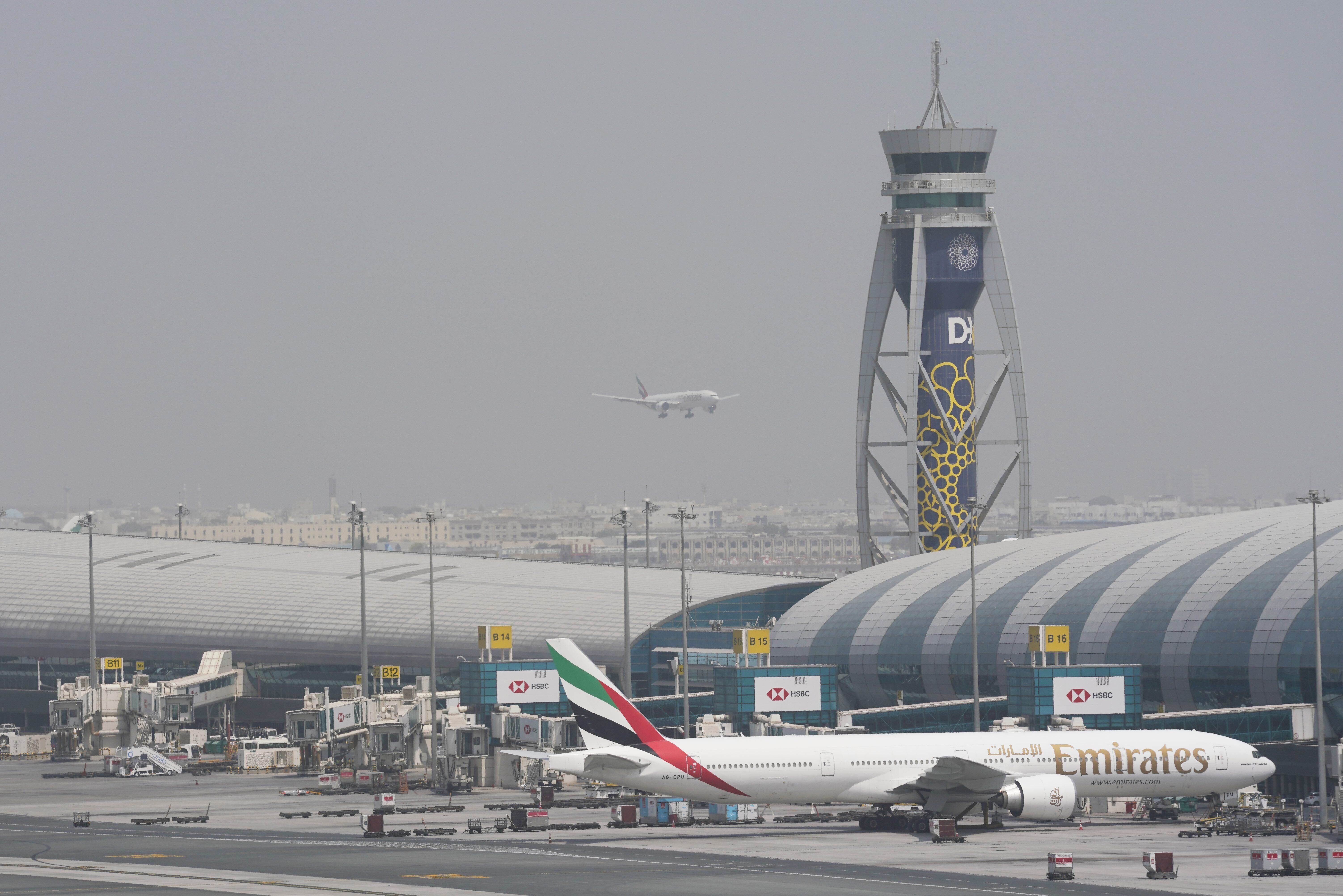FILE - An Emirates Boeing 777 stands at the gate at Dubai International Airport as another prepares to land on the runway in Dubai, United Arab Emirates, Aug. 17, 2022. (AP Photo/Jon Gambrell, File)