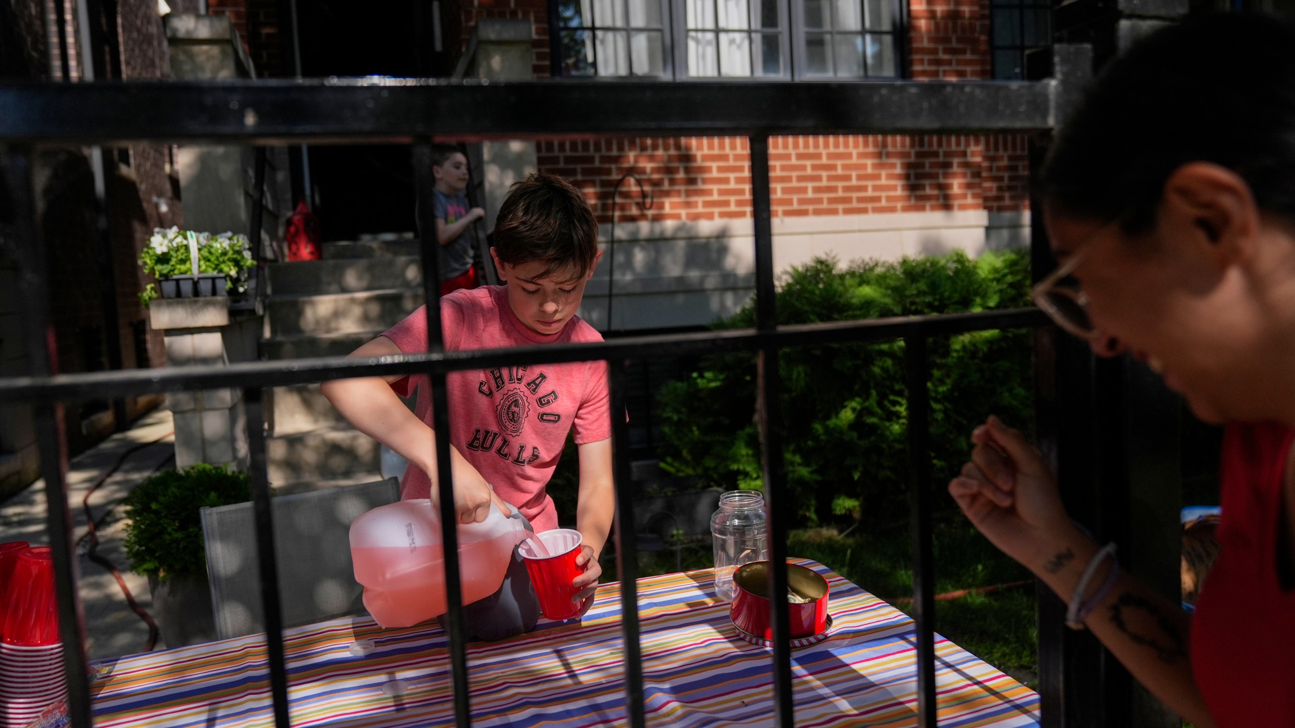 Robby, 12, who did not want to give his last name, sells lemonade in his front yard on a hot Friday, June 20, 2025, in Chicago. (AP Photo/Erin Hooley)