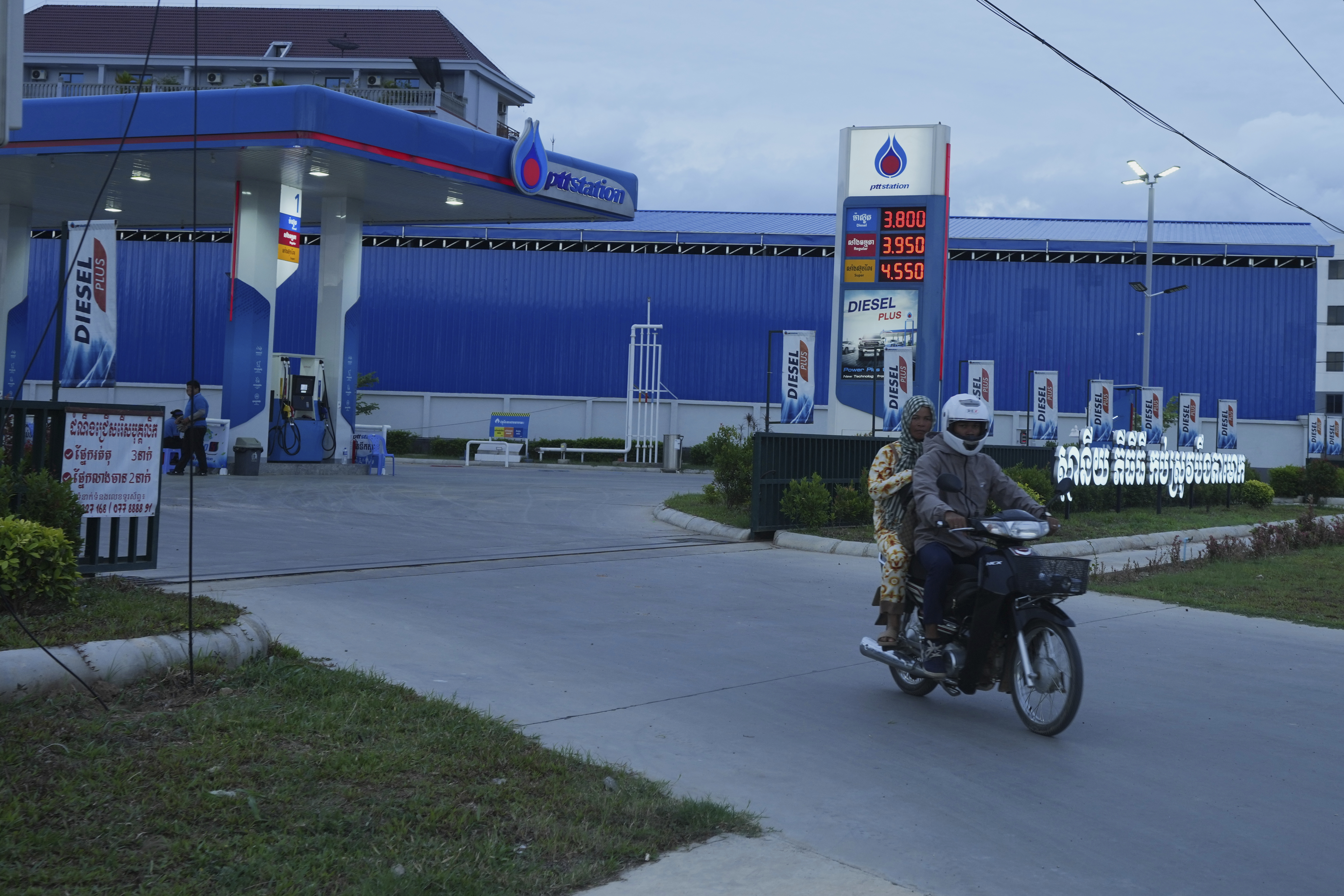 A couple rides on a motorcycle after filling gasoline at a PTT, (Petroleum Authority of Thailand), outside Phnom Penh, Cambodia, Monday, June 23, 2025. (AP Photo/Heng Sinith)