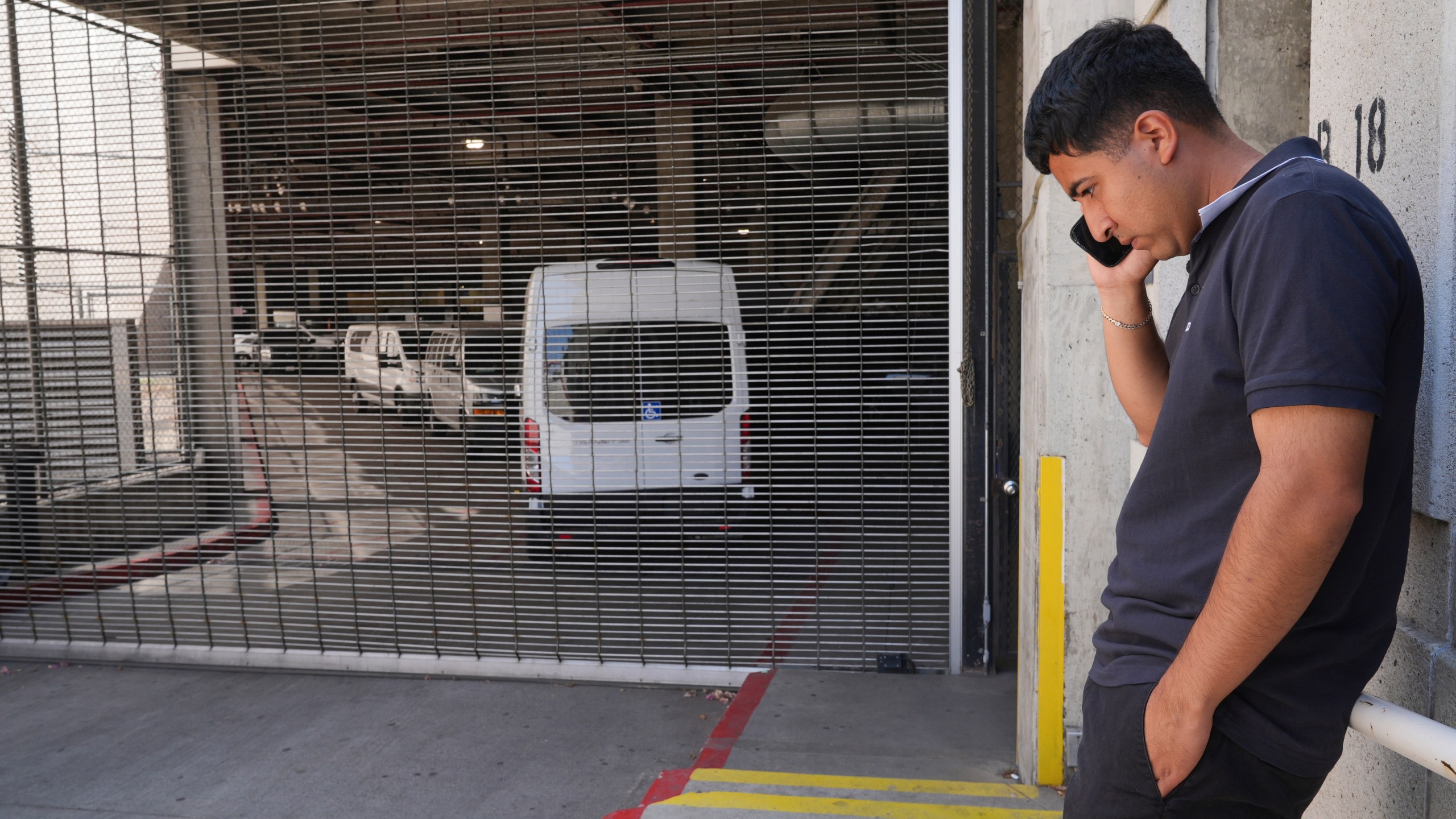 Alejandro Barranco talks on his cell phone outside the Metropolitan Detention Center, where is father Narciso is detained, on Monday, June 23, 2025, in Los Angeles. (AP Photo/Damian Dovarganes)