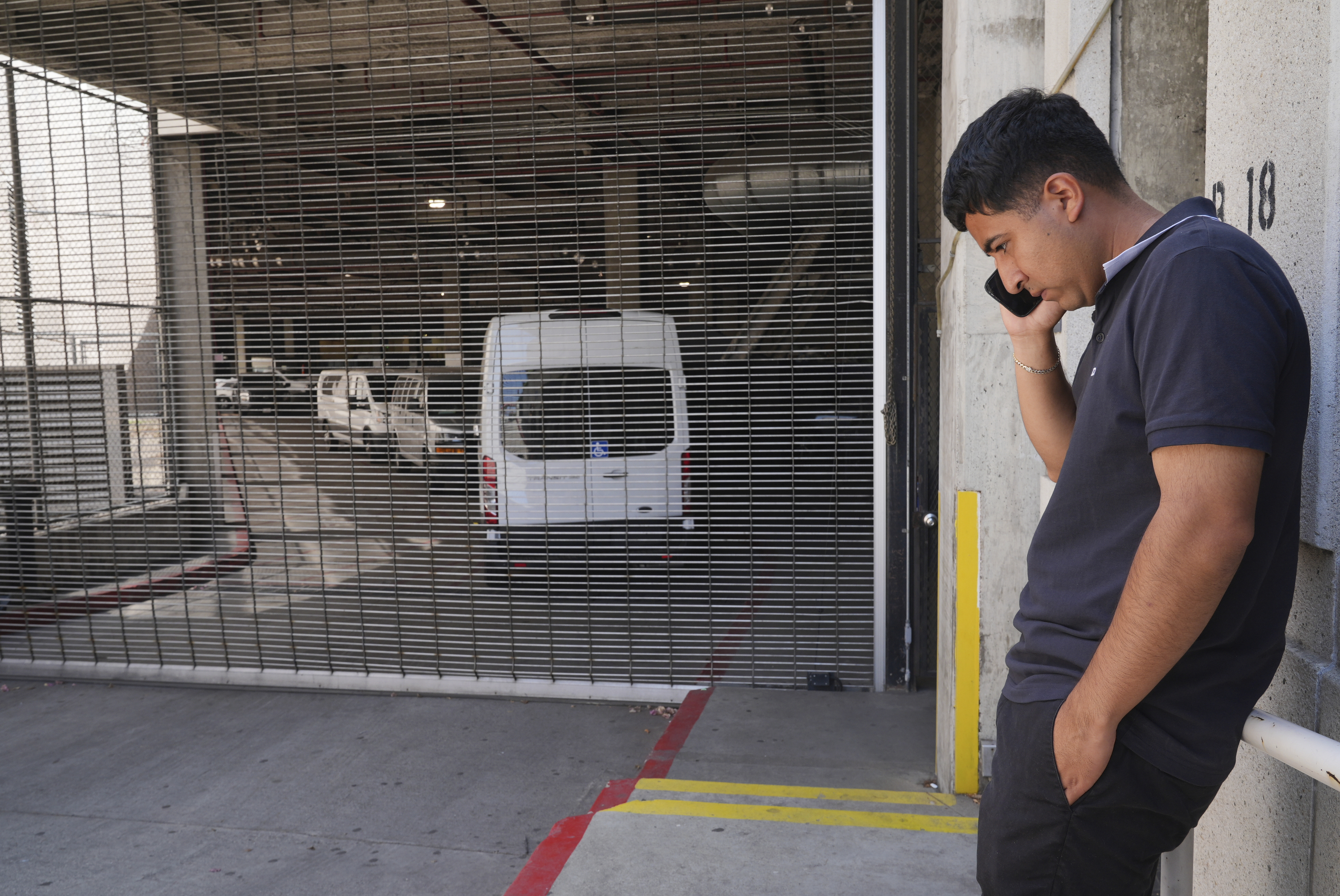 Alejandro Barranco talks on his cell phone outside the Metropolitan Detention Center, where is father Narciso is detained, on Monday, June 23, 2025, in Los Angeles. (AP Photo/Damian Dovarganes)