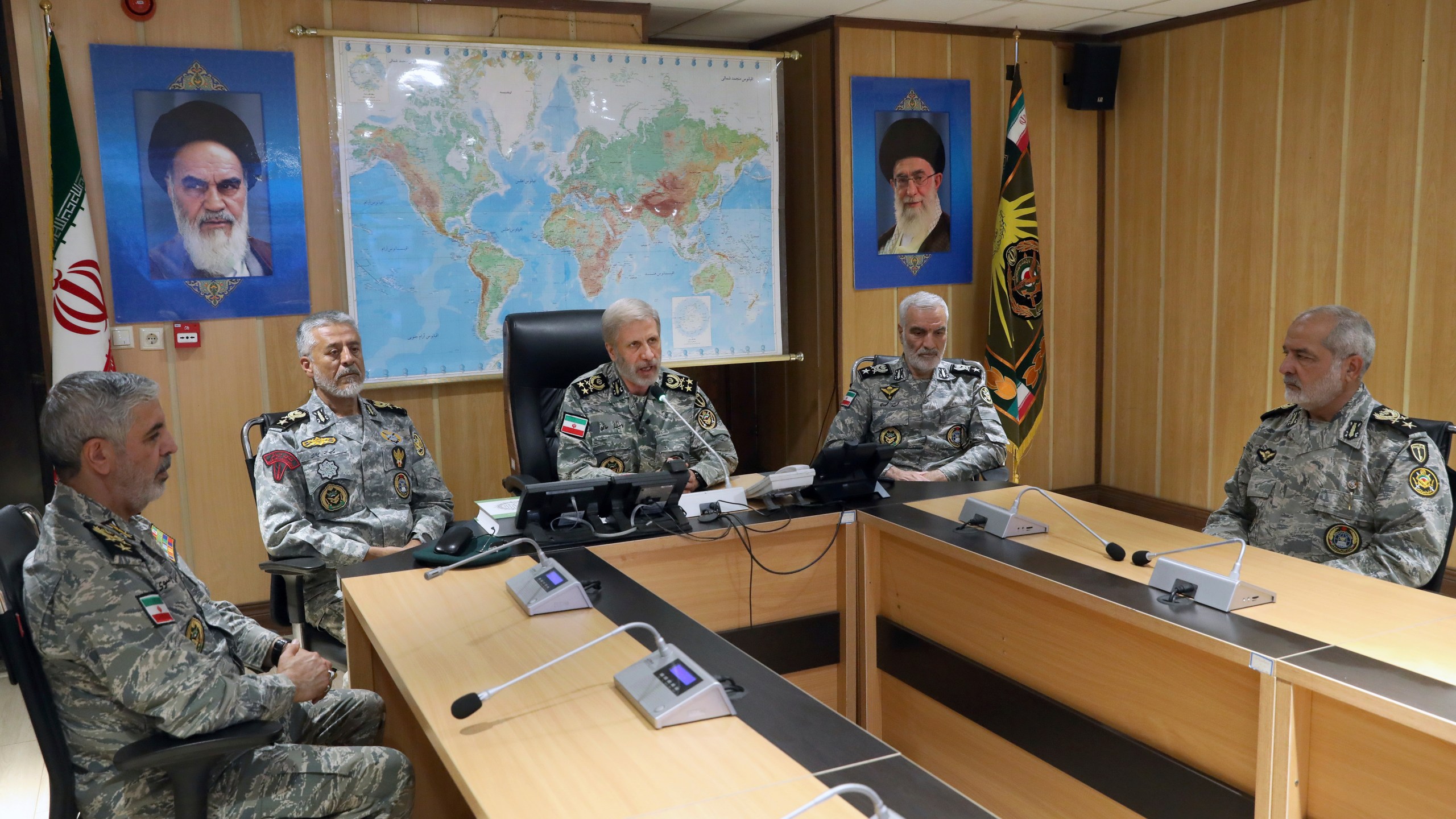 In this photo released on Monday, June 23, 2025, by Iranian army press service, Iran's army commander-in-chief Gen. Amir Hatami, center, accompanied by high ranked army commanders, speaks in a video call with top commanders of the army, in Zolfaghar central headquarters, Iran, as portraits of the late revolutionary founder Ayatollah Khomeini, left, and Supreme Leader Ayatollah Ali Khamenei hang on the wall. (Iranian Army Press Service via AP)