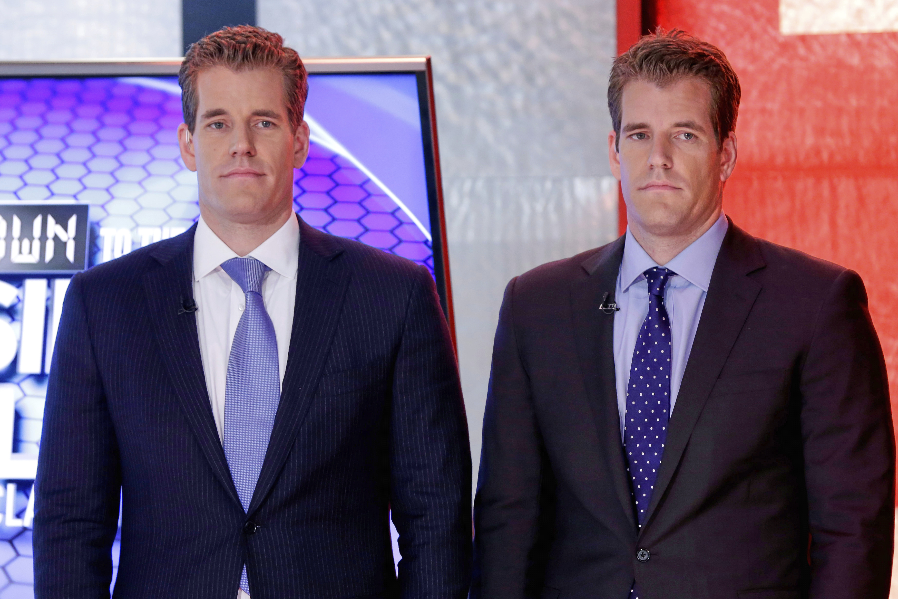 FILE - Cameron Winklevoss, left, and Tyler Winklevoss, founders of Gemini Trust Co., wait to appear on the "Countdown to the Closing Bell with Liz Claman" program, on the Fox Business Network, in New York, Oct. 8, 2015. (AP Photo/Richard Drew, File)