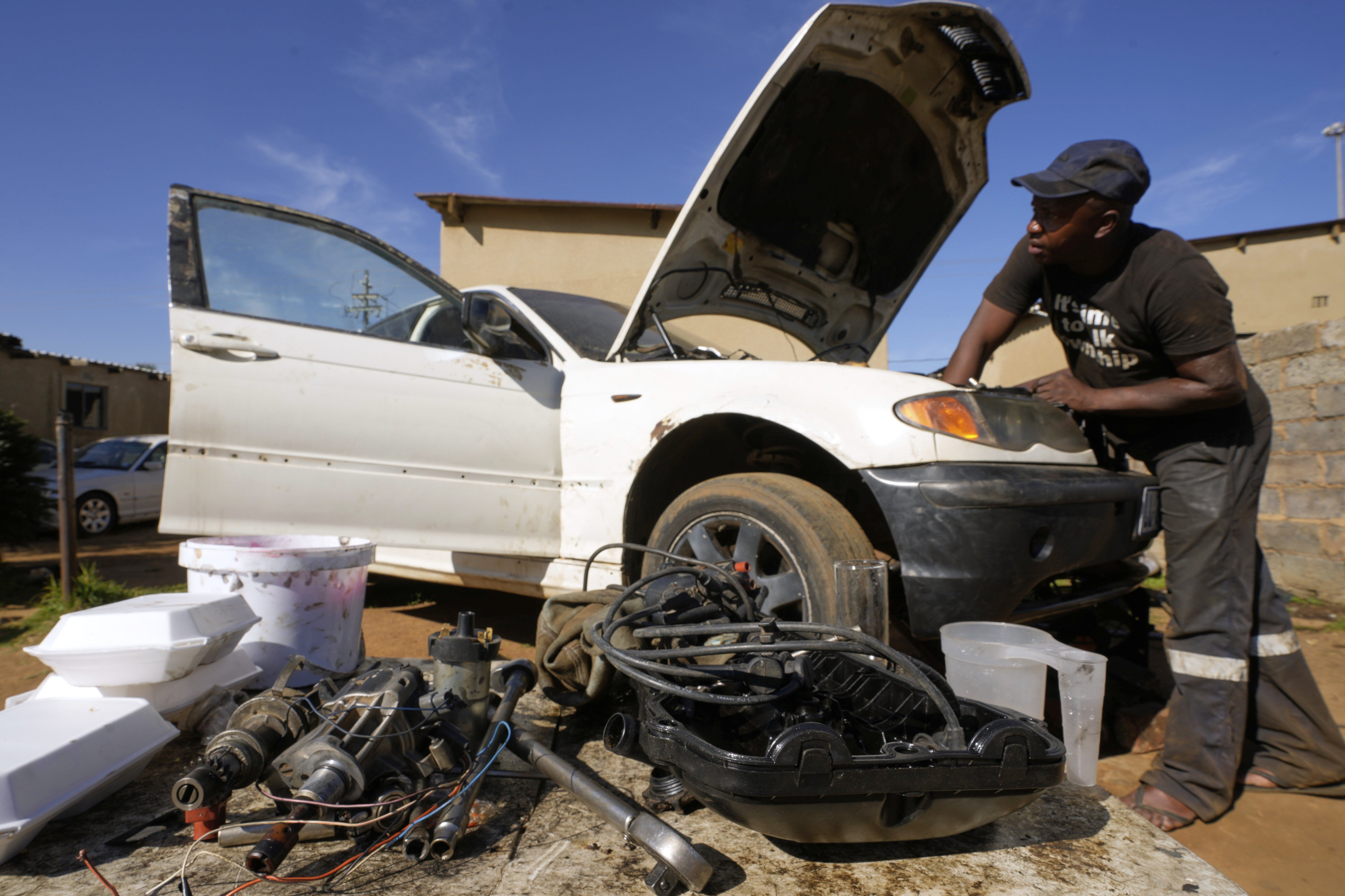Themba Maseko, a 39-year-old mechanic, repairs a BMW car outside his workshop in Brakpan, east of Johannesburg, South Africa, Wednesday, May 14, 2025. (AP Photo/Themba Hadebe)