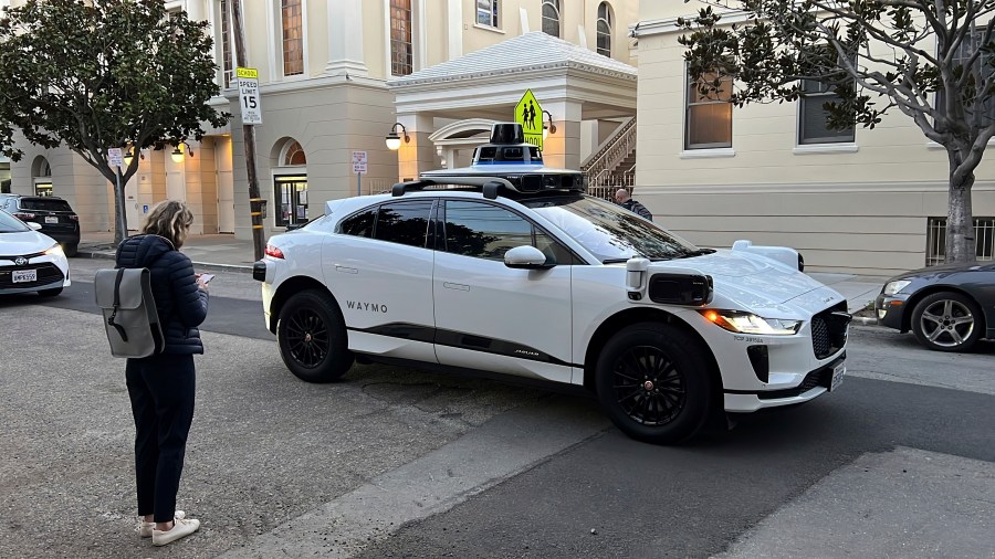 FILE - Waymo communications manager Julia Ilina stands next to a Waymo driverless taxi in San Francisco, on Feb. 15, 2023. (AP Photo/Terry Chea, File)