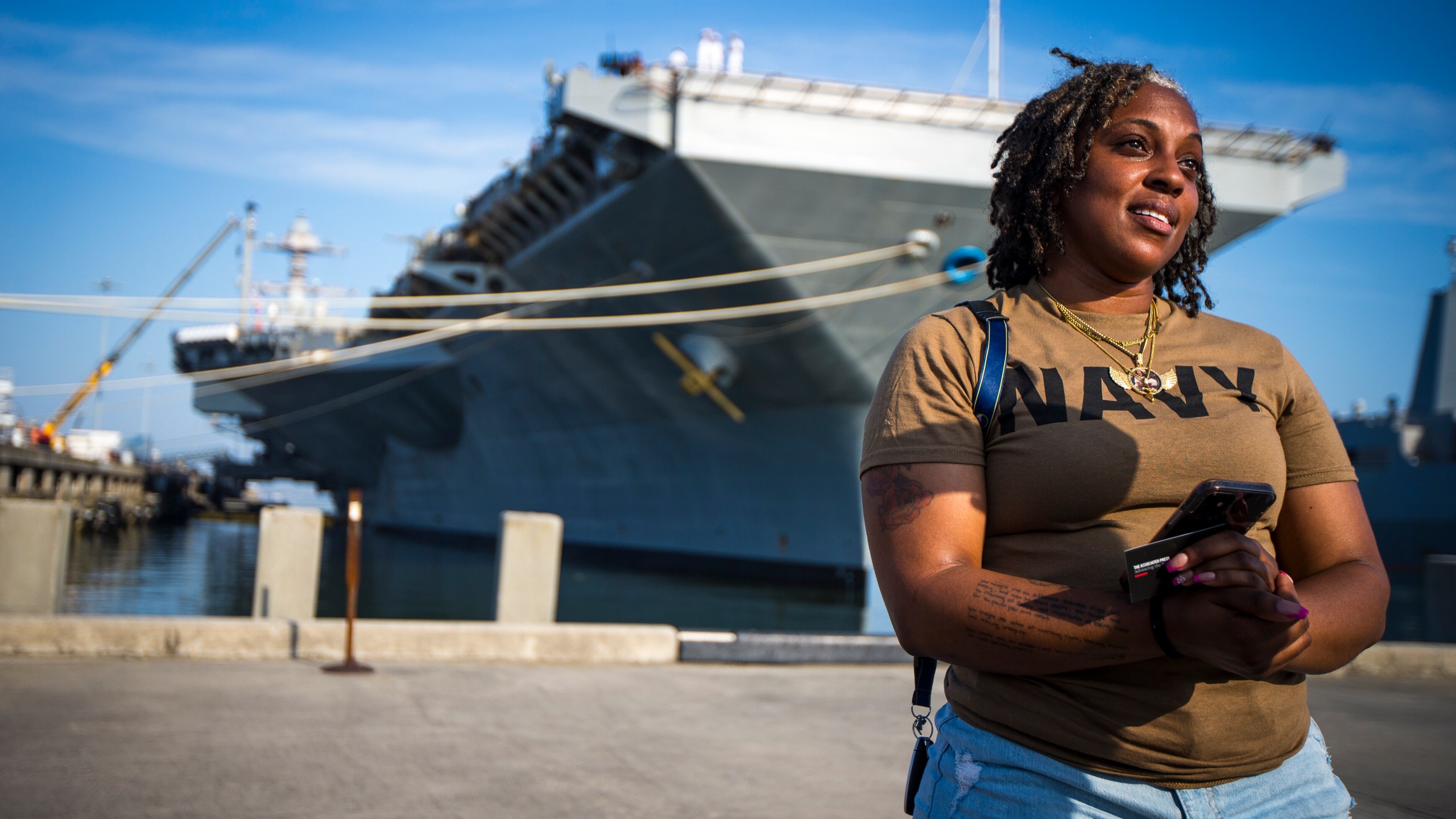 Latoya Savoy stands in front of the USS Gerald R. Ford aircraft carrier leaves Naval Station Norfolk with her daughter (unnamed), a U.S. Navy sailor who works in aviation ordinance on Tuesday, June 24, 2025, in Norfolk, Va. (AP Photo/John Clark)
