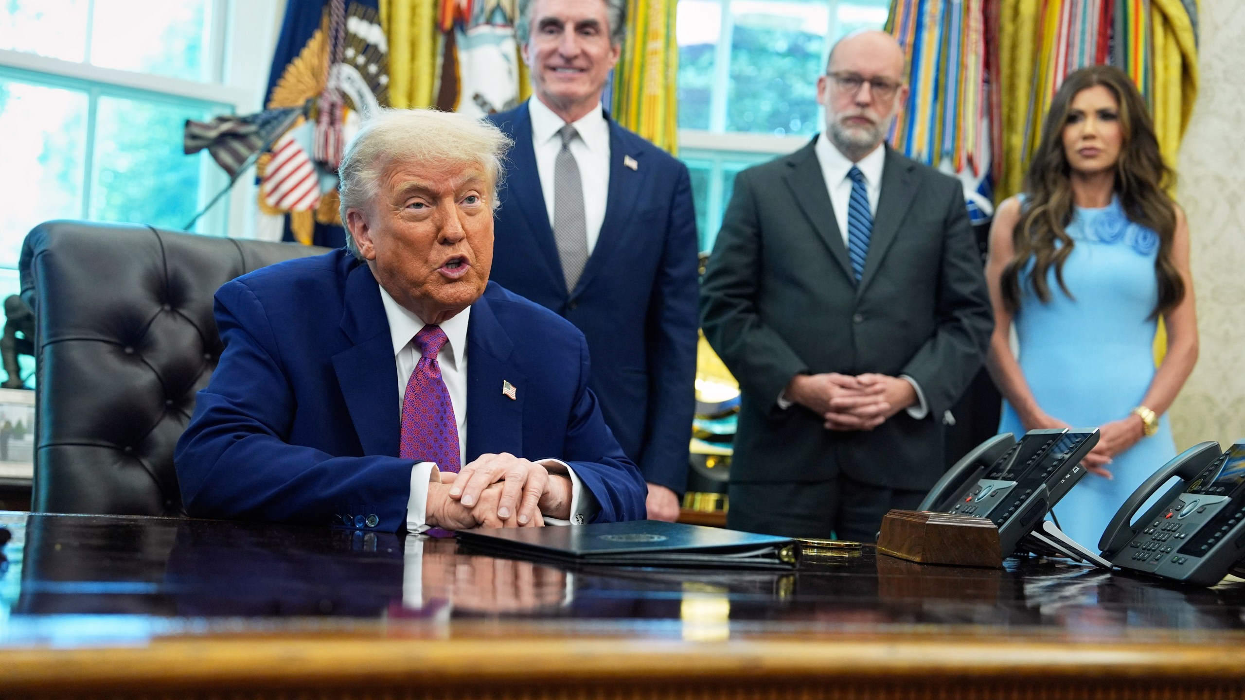 President Donald Trump speaks to the media in the Oval Office at the White House, Tuesday, June 10, 2025, in Washington, as Interior Secretary Doug Burgum, Director of the Office of Management and Budget Russell Vought and Secretary of Homeland Security Kristi Noem, look on. ( (AP Photo/Evan Vucci)