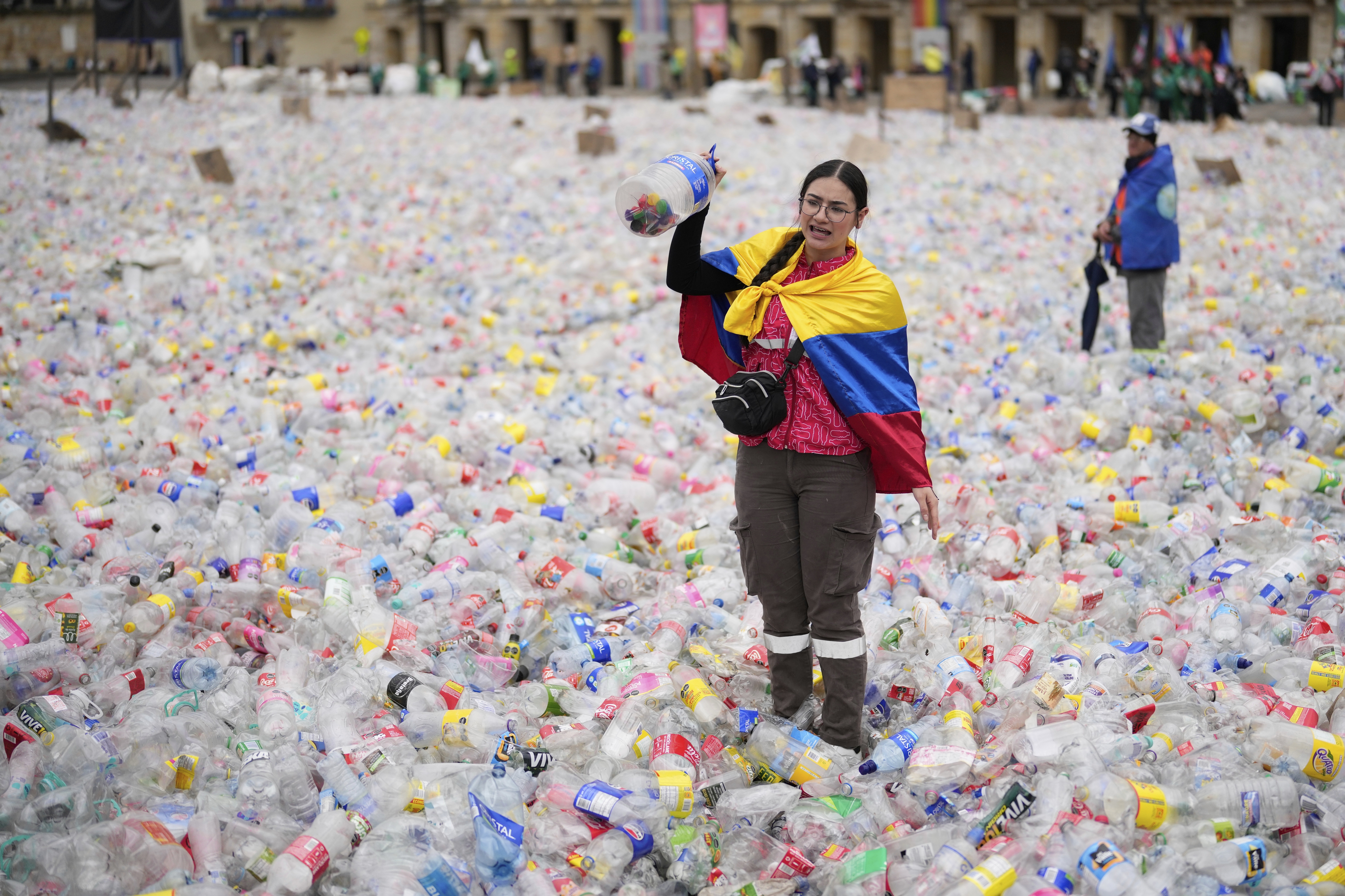 A recycler stands amid plastic bottles blanketing Plaza Bolivar in Bogota, Colombia, as part of a protest against what recyclers consider to be too low a price paid to them by companies that buy recycled materials, Tuesday, June 24, 2025. (AP Photo/Fernando Vergara)