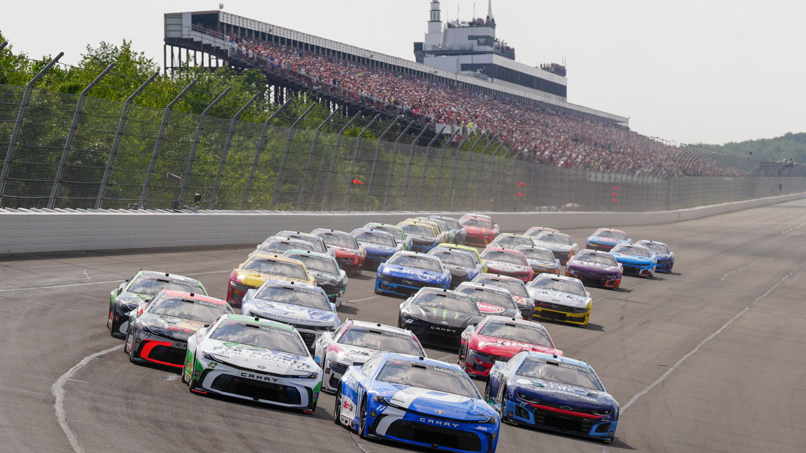 Denny Hamlin (11) leads the field into Turn 1 to start the NASCAR Cup Series auto race at Pocono Raceway, Sunday, June 22, 2025, in Long Pond, Pa. (AP Photo/Derik Hamilton)