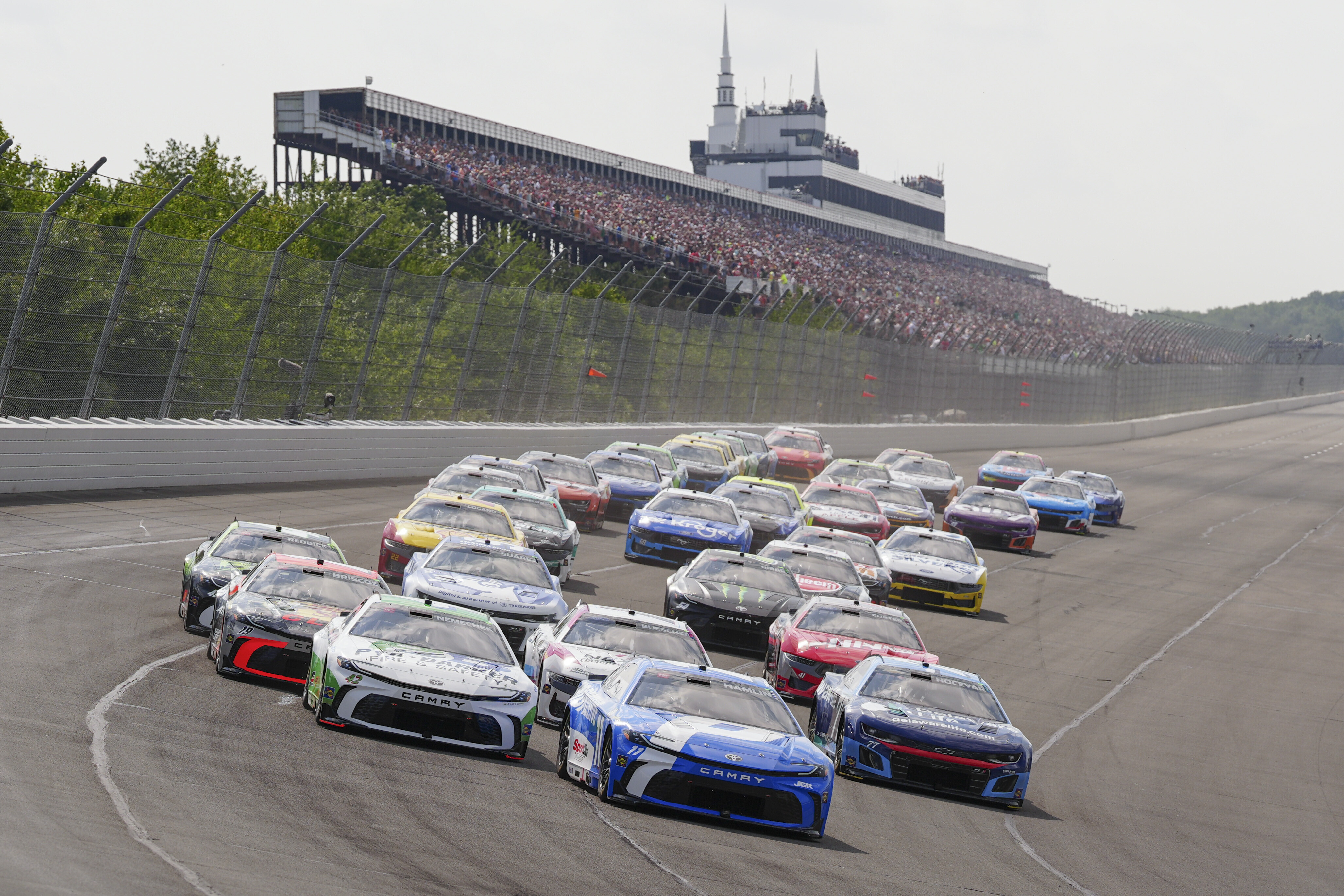 Denny Hamlin (11) leads the field into Turn 1 to start the NASCAR Cup Series auto race at Pocono Raceway, Sunday, June 22, 2025, in Long Pond, Pa. (AP Photo/Derik Hamilton)