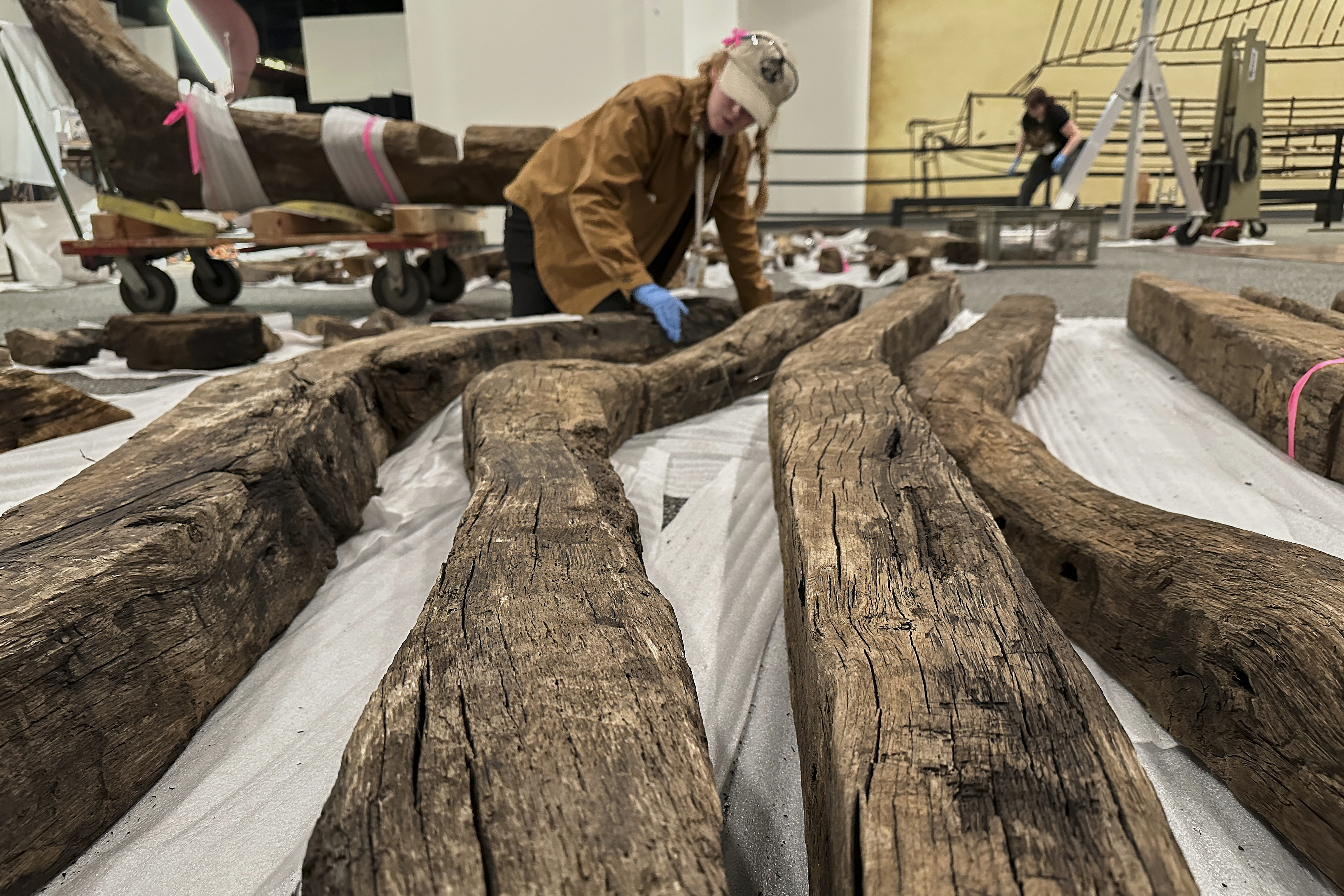 Research assistant Alyssa Carpenter inspects timbers from of a wooden Revolutionary War-era gunboat to prepare for the craft's partial reconstruction at the New York State Museum, Friday, May 30, 2025, in Albany, New York (AP Photo/Michael Hill)
