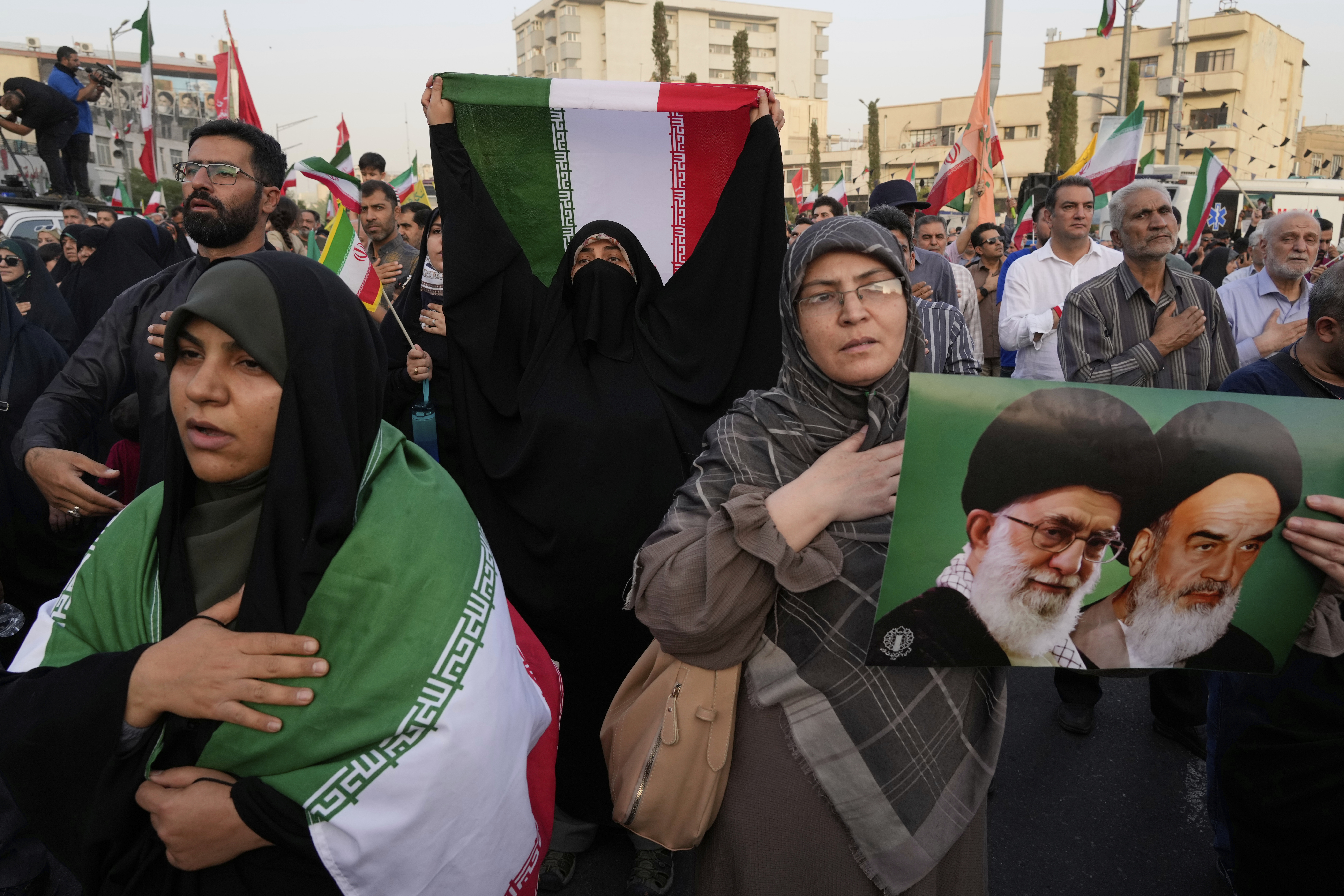 Iranian protesters hold their country's flags and a poster of Supreme Leader Ayatollah Ali Khamenei, left, and the late revolutionary founder Ayatollah Khomeini in an anti-U.S. and anti-Israeli rally at Enqelab-e-Eslami (Islamic Revolution) square in downtown Tehran, Iran, Tuesday, June 24, 2025. (AP Photo/Vahid Salemi)
