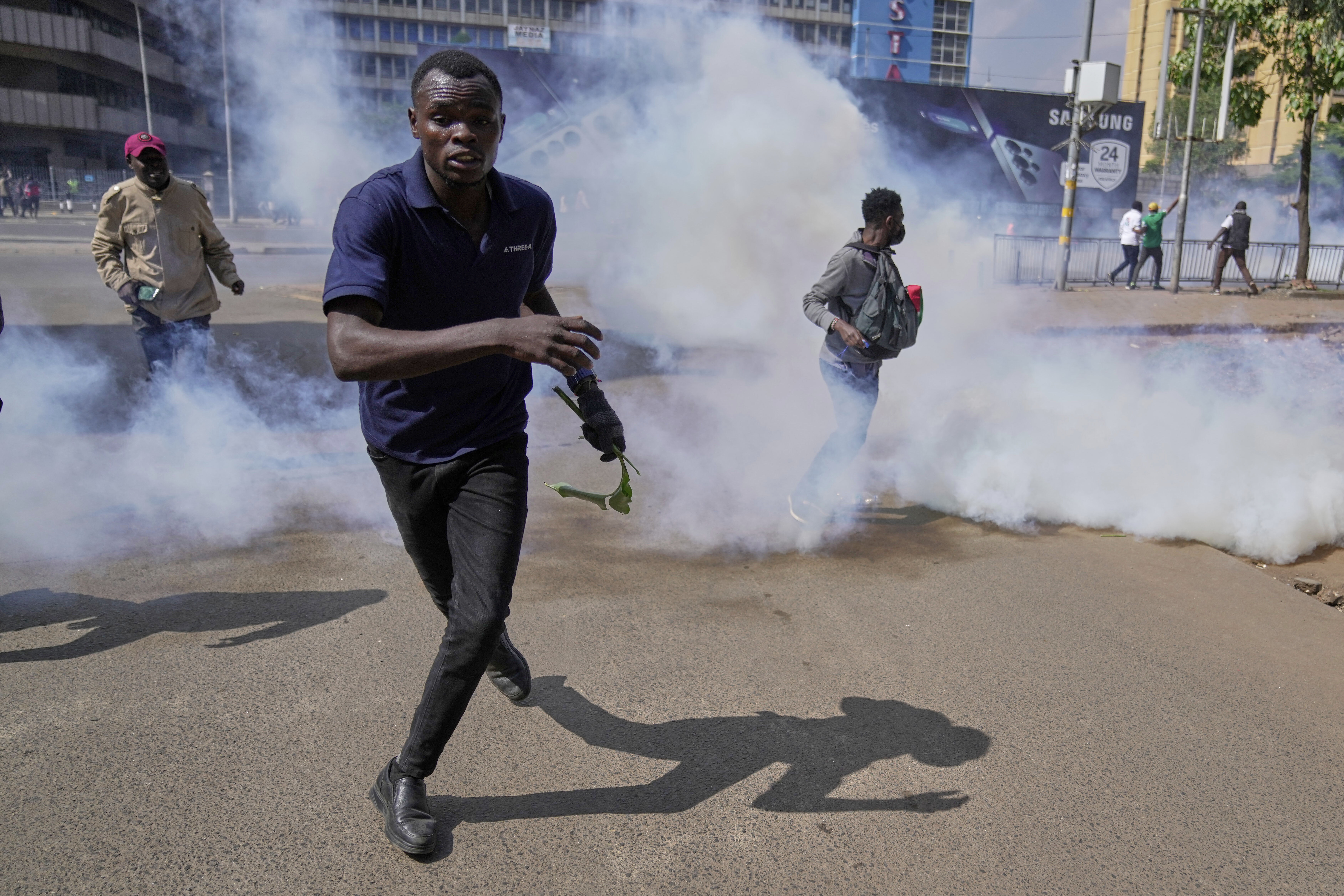 Protesters scatter as police fire teargas at them during a demonstration on the one-year anniversary of deadly anti-tax demonstrations in downtown Nairobi, Kenya, Wednesday, June 25, 2025. (AP Photo/Brian Inganga)
