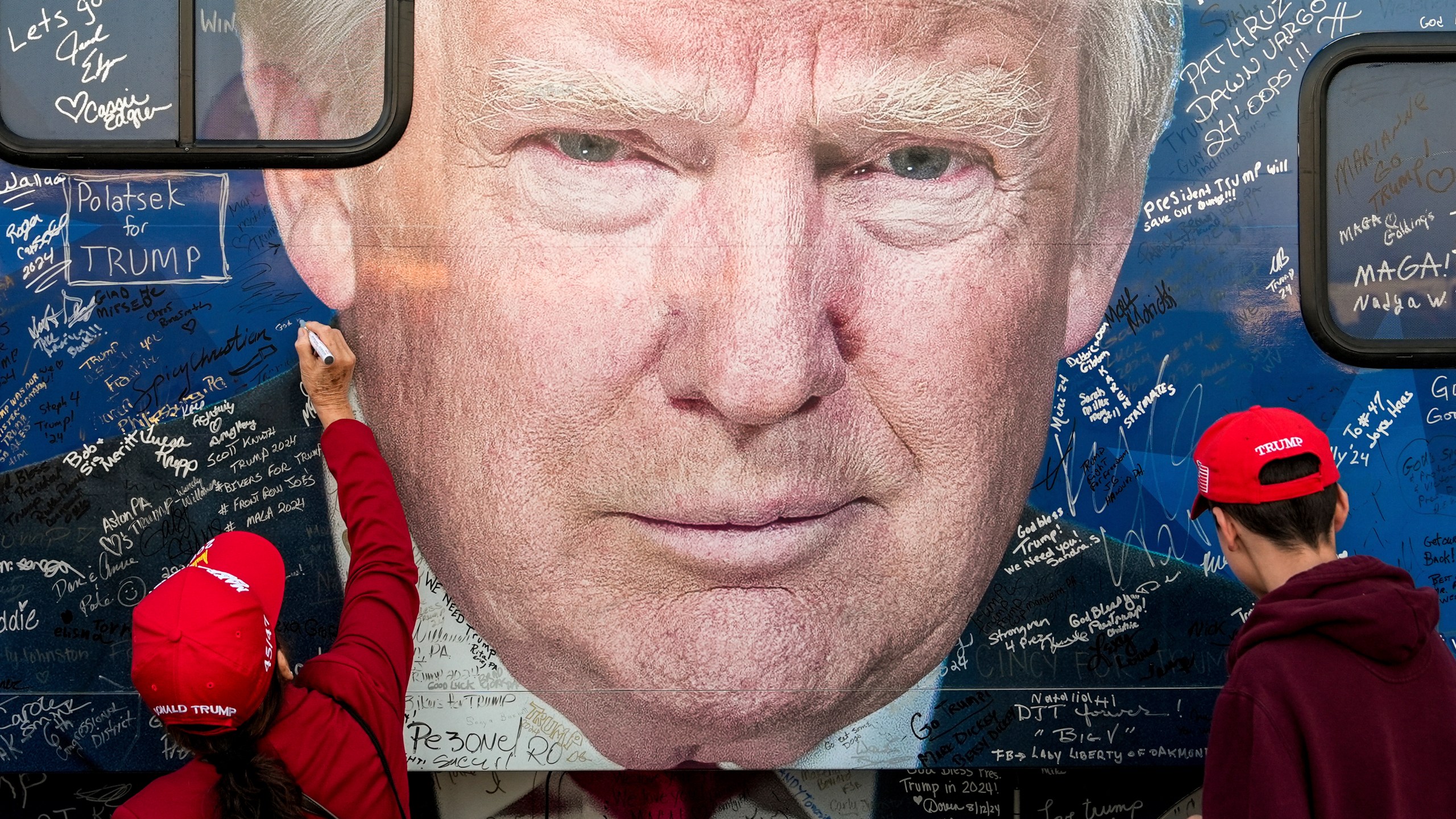 FILE - Supporters of Republican presidential nominee former President Donald Trump sign a bus before a campaign rally at the Butler Farm Show, Oct. 5, 2024, in Butler, Pa. (AP Photo/Julia Demaree Nikhinson, File)