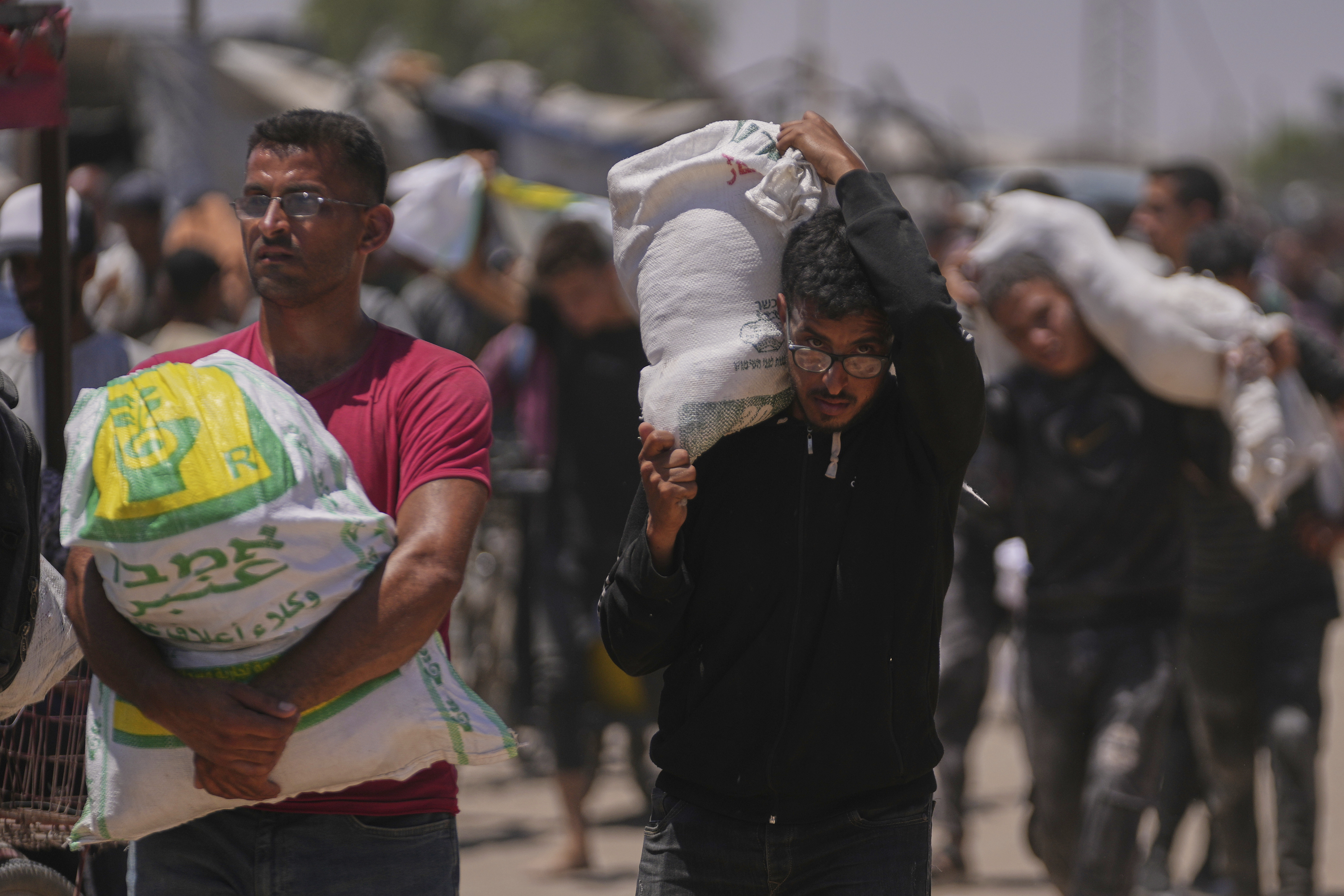 Palestinians carry bags containing food and humanitarian aid packages delivered by the Gaza Humanitarian Foundation, a U.S.-backed organization, in Rafah, southern Gaza Strip, Wednesday, June 25, 2025. (AP Photo/Abdel Kareem Hana)