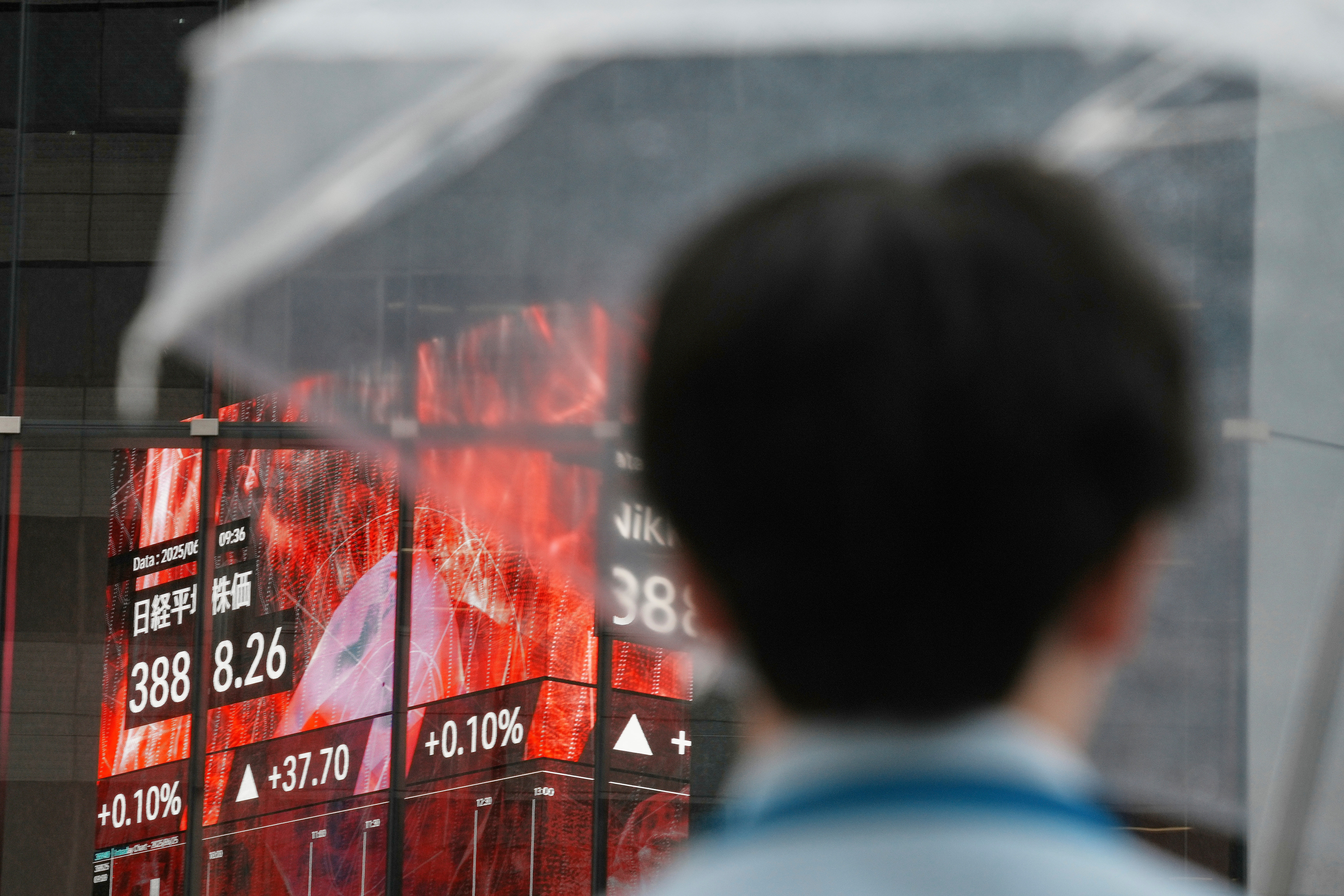A person stands in front of an electronic stock board showing Japan's Nikkei index at a securities firm Wednesday, June 25, 2025, in Tokyo. (AP Photo/Eugene Hoshiko)
