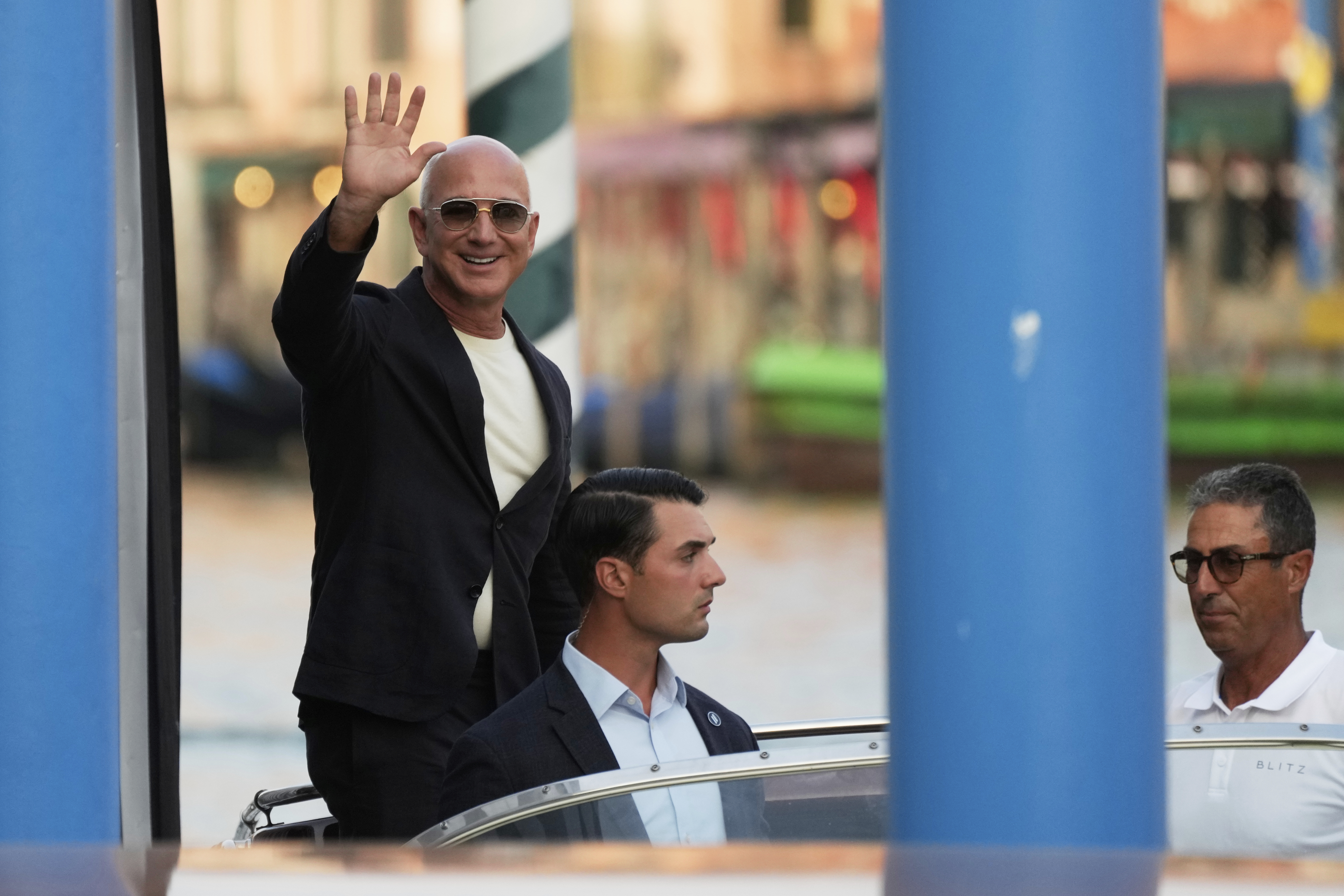 Amazon multi-billionaire founder Jeff Bezos waves as he leaves by boat a hotel in Venice, Italy, on Wednesday, June 25, 2025, ahead of festivities in the lagoon city reportedly linked to his wedding with Lauren Sanchez. (AP Photo/Luca Bruno)