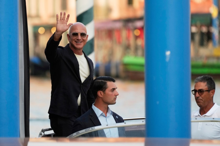 Amazon multi-billionaire founder Jeff Bezos waves as he leaves by boat a hotel in Venice, Italy, on Wednesday, June 25, 2025, ahead of festivities in the lagoon city reportedly linked to his wedding with Lauren Sanchez. (AP Photo/Luca Bruno)