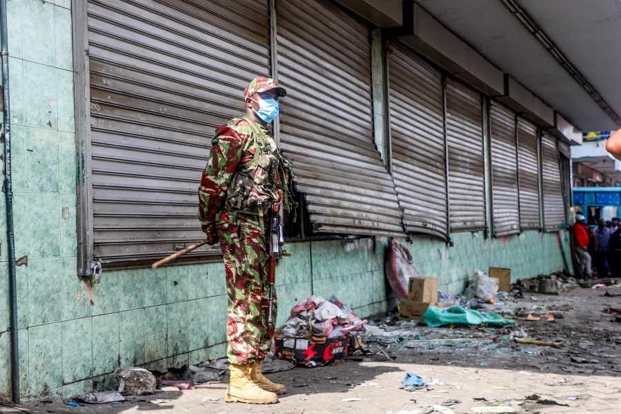 A police officer stands guard at a vandalized shop following the one-year anniversary of deadly anti-tax demonstrations in Nairobi, Kenya, Thursday, June 26, 2025. (AP Photo/Patrick Ngugi)