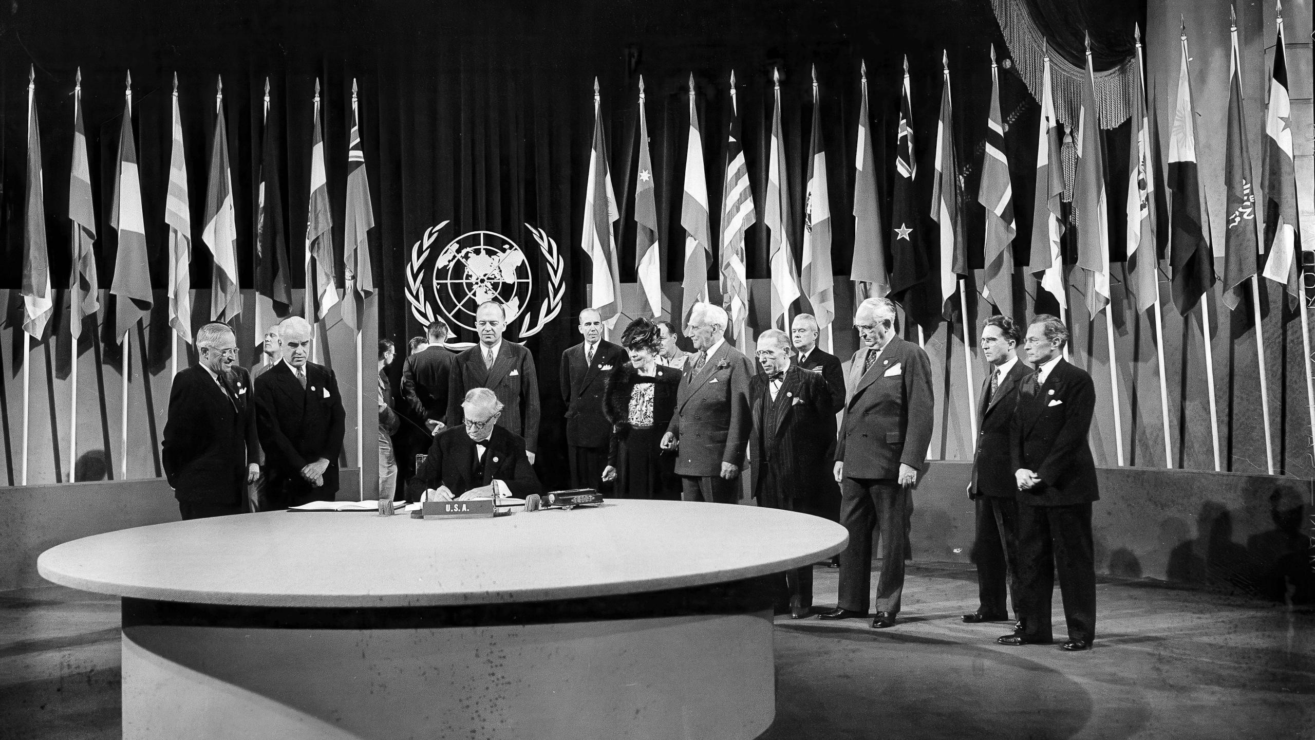 FILE - President Harry S. Truman and the entire American delegation watch as Sen. Tom Connally signs the United Nations Charter in San Francisco, June 26, 1945. Standing, from left, after Truman are Secretary of State Edward Stettinius Jr.; Harold Edward Stassen; unidentified; Dean Virginia Gildersleeve; Rep. Charles A. Eaton; Rep. Sol Bloom, and Sen. Arthur Vandenberg. (AP Photo, File)