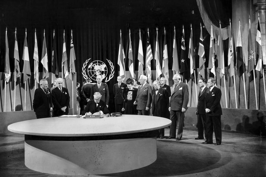 FILE - President Harry S. Truman and the entire American delegation watch as Sen. Tom Connally signs the United Nations Charter in San Francisco, June 26, 1945. Standing, from left, after Truman are Secretary of State Edward Stettinius Jr.; Harold Edward Stassen; unidentified; Dean Virginia Gildersleeve; Rep. Charles A. Eaton; Rep. Sol Bloom, and Sen. Arthur Vandenberg. (AP Photo, File)