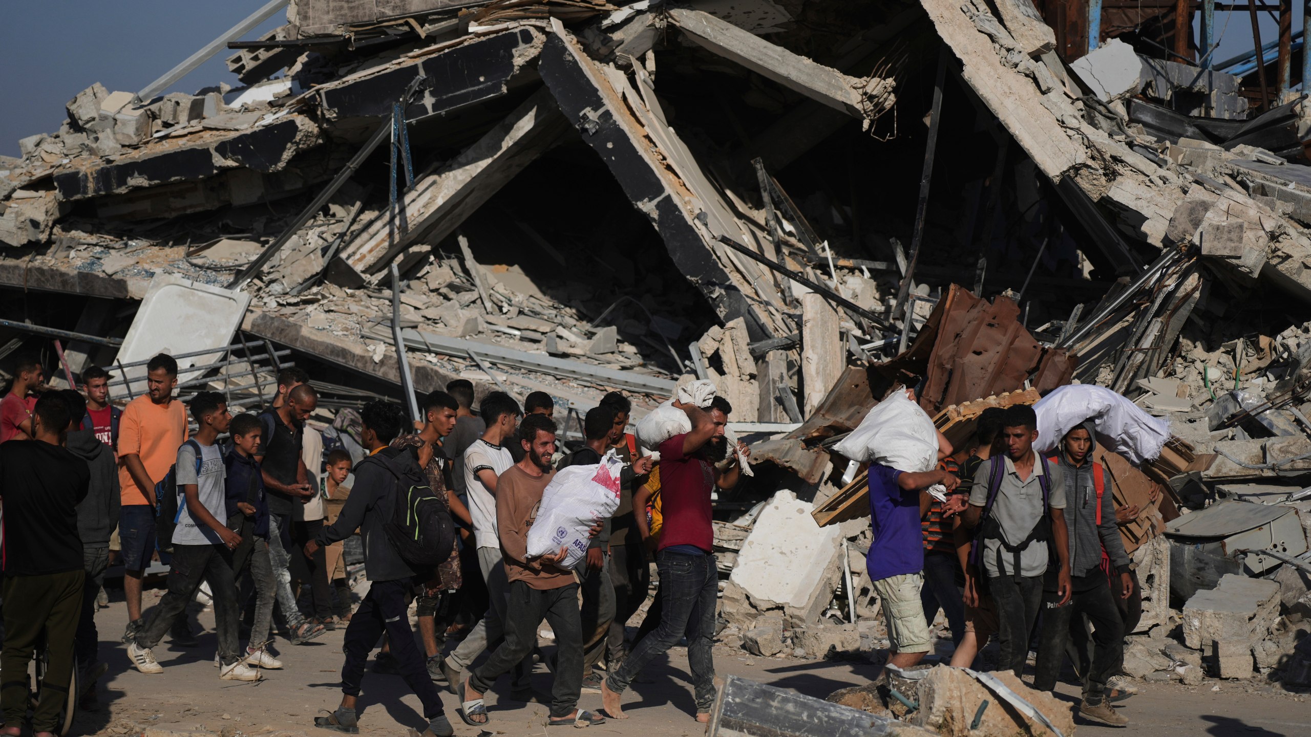 Palestinians carry humanitarian aid packages distributed by the Gaza Humanitarian Foundation operated by the U.S.-backed organization in Khan Younis, southern Gaza Strip, Thursday, June 26, 2025. (AP Photo/Abdel Kareem Hana)