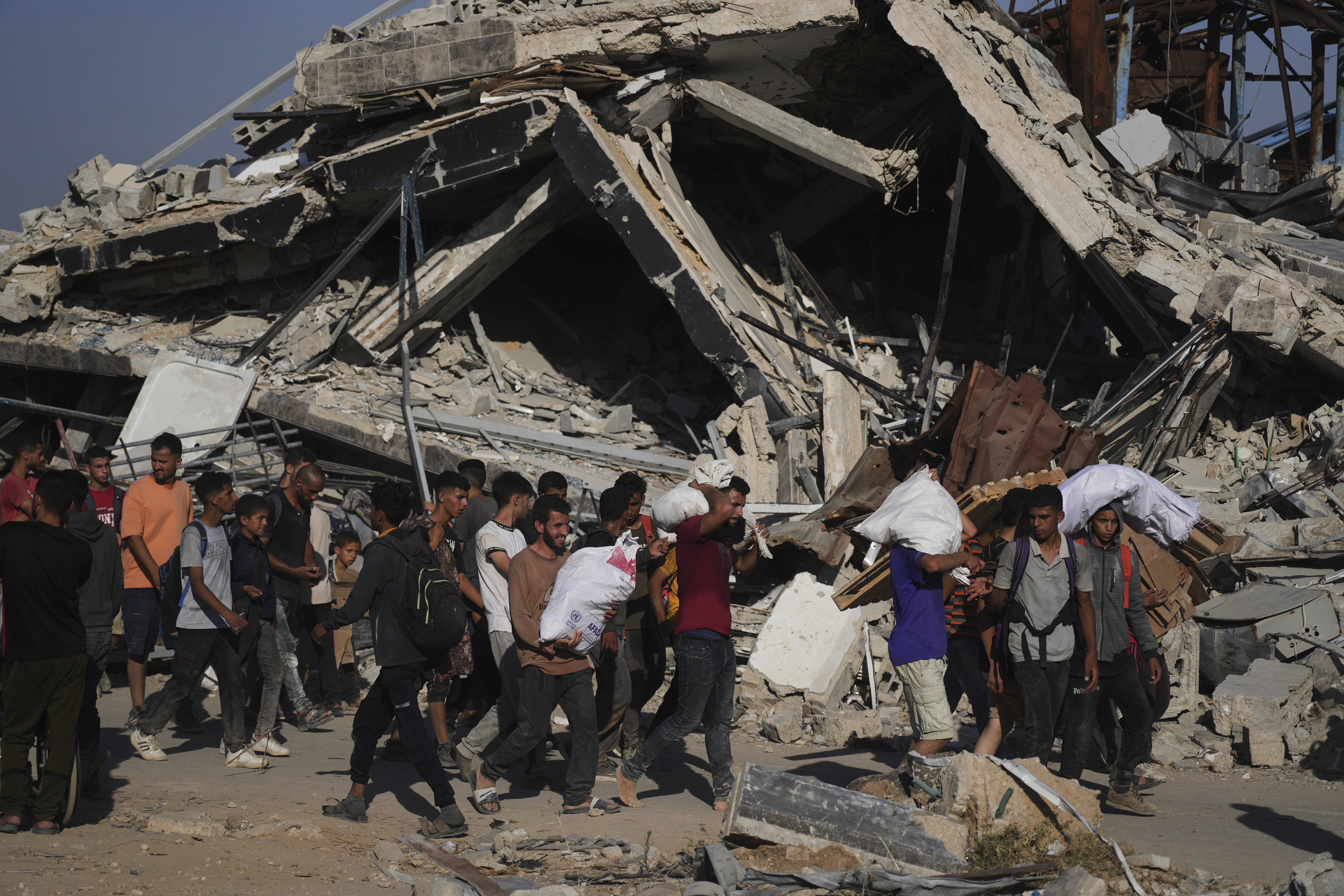 Palestinians carry humanitarian aid packages distributed by the Gaza Humanitarian Foundation operated by the U.S.-backed organization in Khan Younis, southern Gaza Strip, Thursday, June 26, 2025. (AP Photo/Abdel Kareem Hana)
