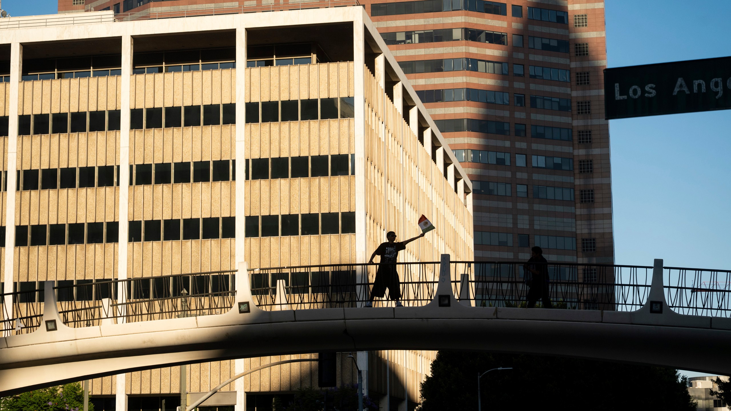A protester against immigration raids waves a flag in front of the 300 North Los Angeles Street Federal Building on Sunday, June 15, 2025, in Los Angeles. (AP Photo/Noah Berger)