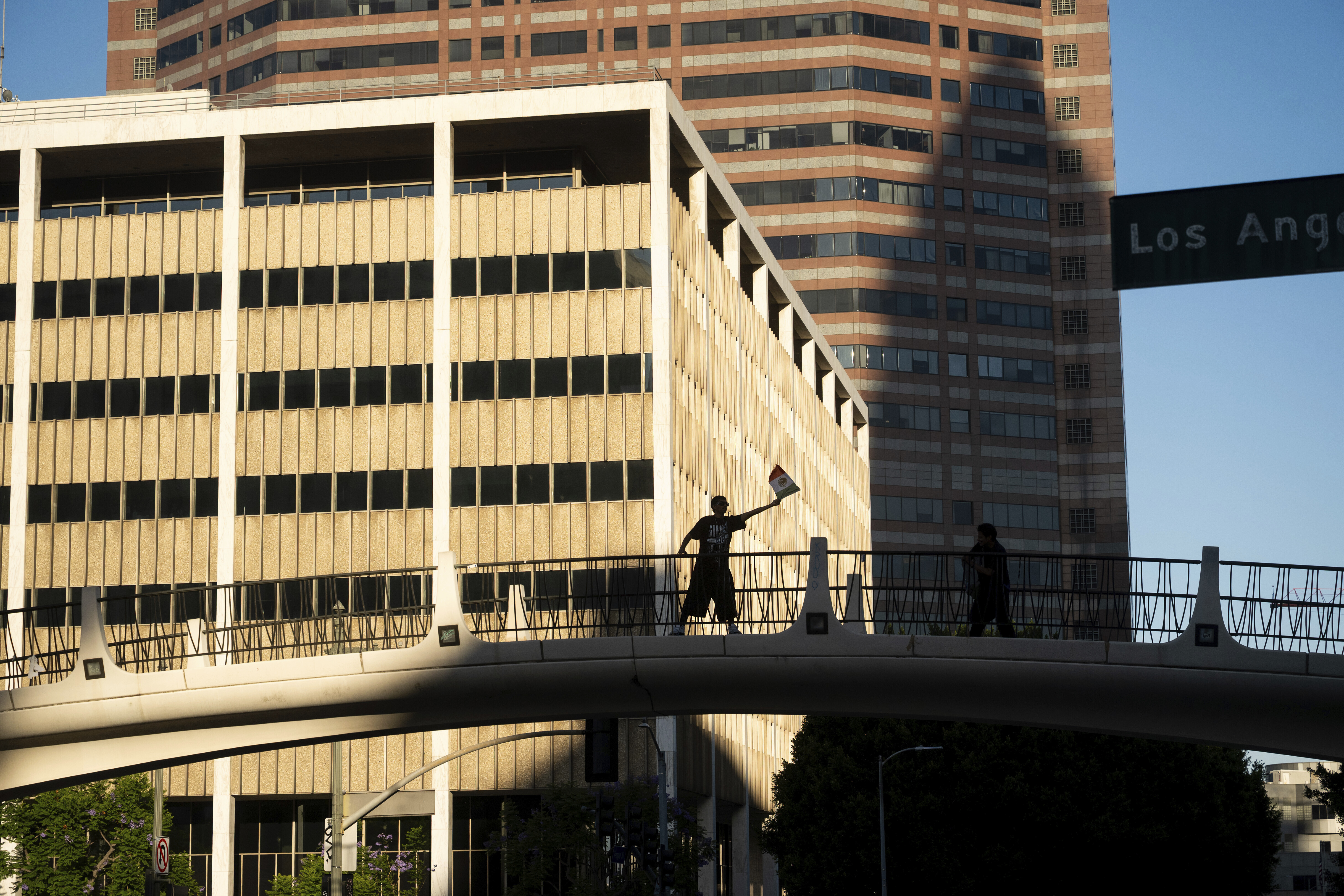 A protester against immigration raids waves a flag in front of the 300 North Los Angeles Street Federal Building on Sunday, June 15, 2025, in Los Angeles. (AP Photo/Noah Berger)