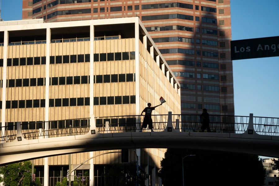 A protester against immigration raids waves a flag in front of the 300 North Los Angeles Street Federal Building on Sunday, June 15, 2025, in Los Angeles. (AP Photo/Noah Berger)