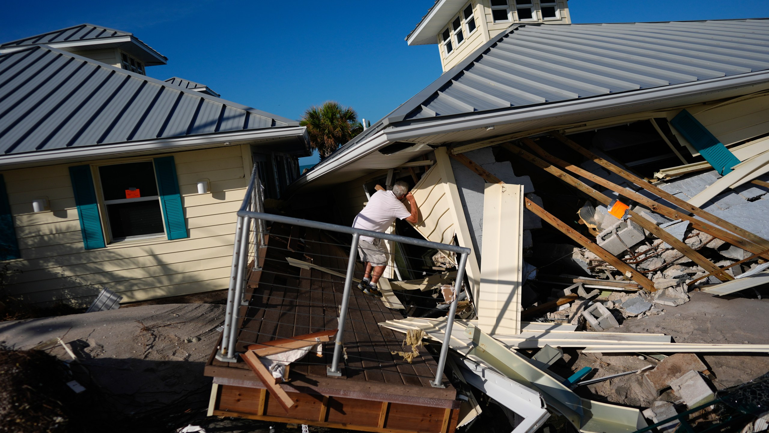 FILE - A property owner, who preferred not to give his name, peers into the remains of the second floor unit where he lived with his wife while renting out the other units, on Manasota Key, in Englewood, Fla., following the passage of Hurricane Milton, Oct. 13, 2024. (AP Photo/Rebecca Blackwell, File)