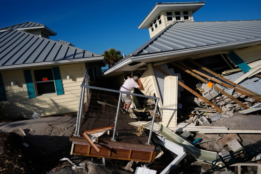 FILE - A property owner, who preferred not to give his name, peers into the remains of the second floor unit where he lived with his wife while renting out the other units, on Manasota Key, in Englewood, Fla., following the passage of Hurricane Milton, Oct. 13, 2024. (AP Photo/Rebecca Blackwell, File)