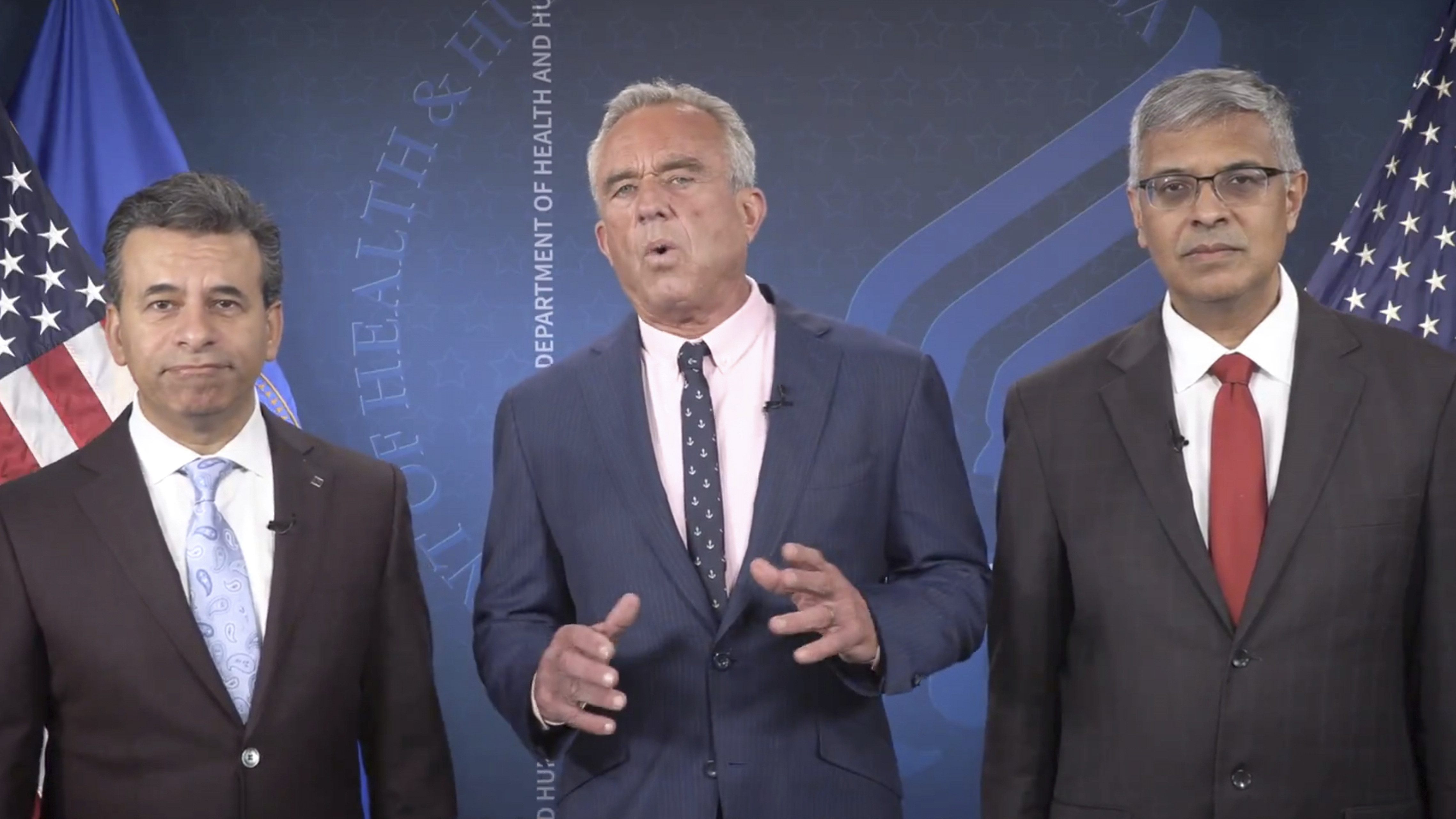 This image from video provided by the Department of Health and Human Services shows Health and Human Services Secretary Robert F. Kennedy Jr. speaking alongside Food and Drug Administration administrator Dr. Martin Makary, left, and Dr. Jay Bhattacharya, director of the National Institutes of Health, as they announce that the government would no longer endorse the COVID-19 vaccine for healthy children or pregnant women. (Health and Human Services via AP)