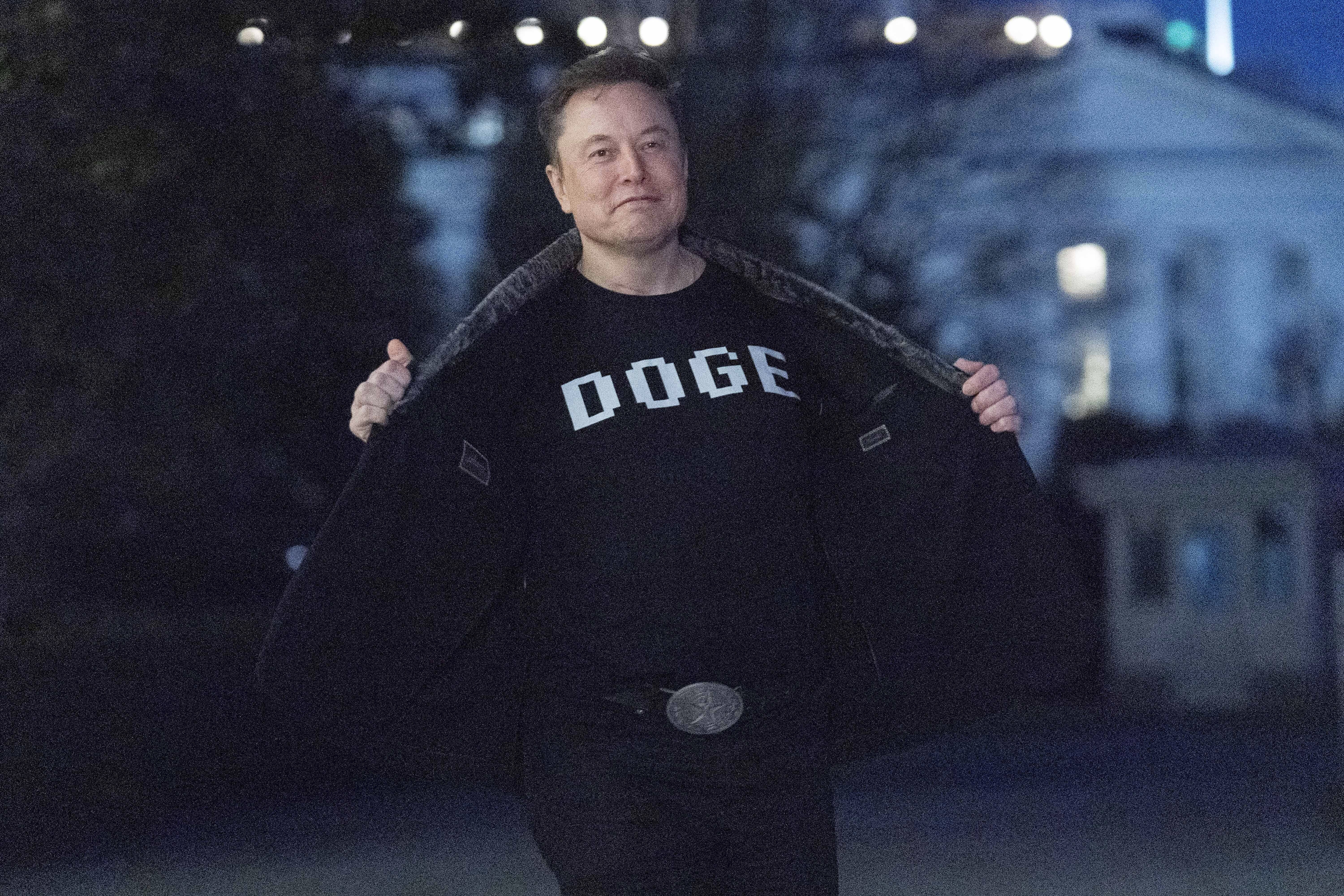 FILE - Elon Musk flashes his t-shirt that reads "DOGE" to the media as he walks on South Lawn of the White House, in Washington, March 9, 2025. (AP Photo/Jose Luis Magana, File)
