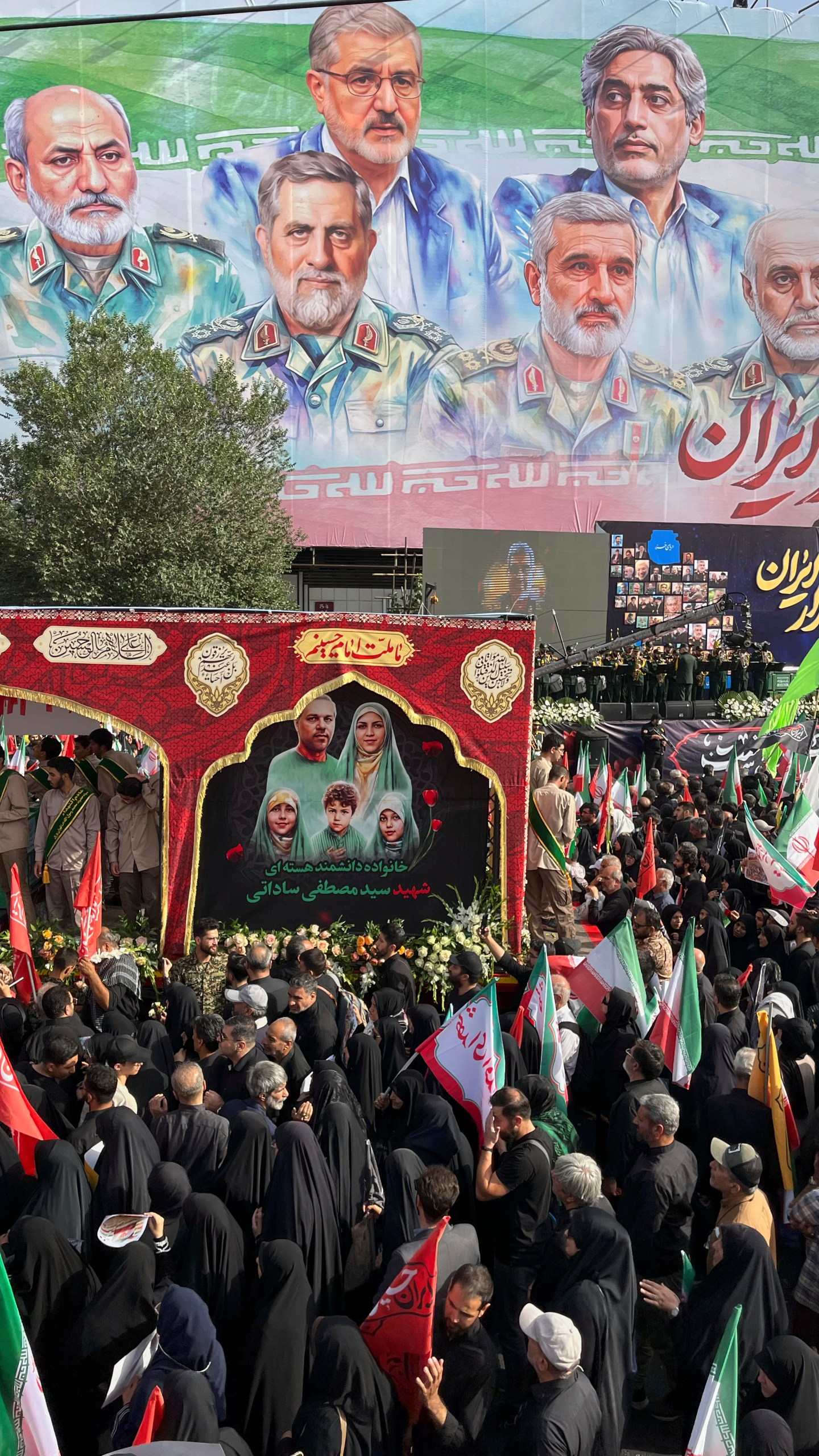 People mourn over the flag-draped coffins of Iranian army generals, nuclear scientists and their family members who were killed in Israeli strikes, during a funeral ceremony in Tehran. Iran, Saturday, June 28, 2025. (AP Photo/Vahid Salemi)