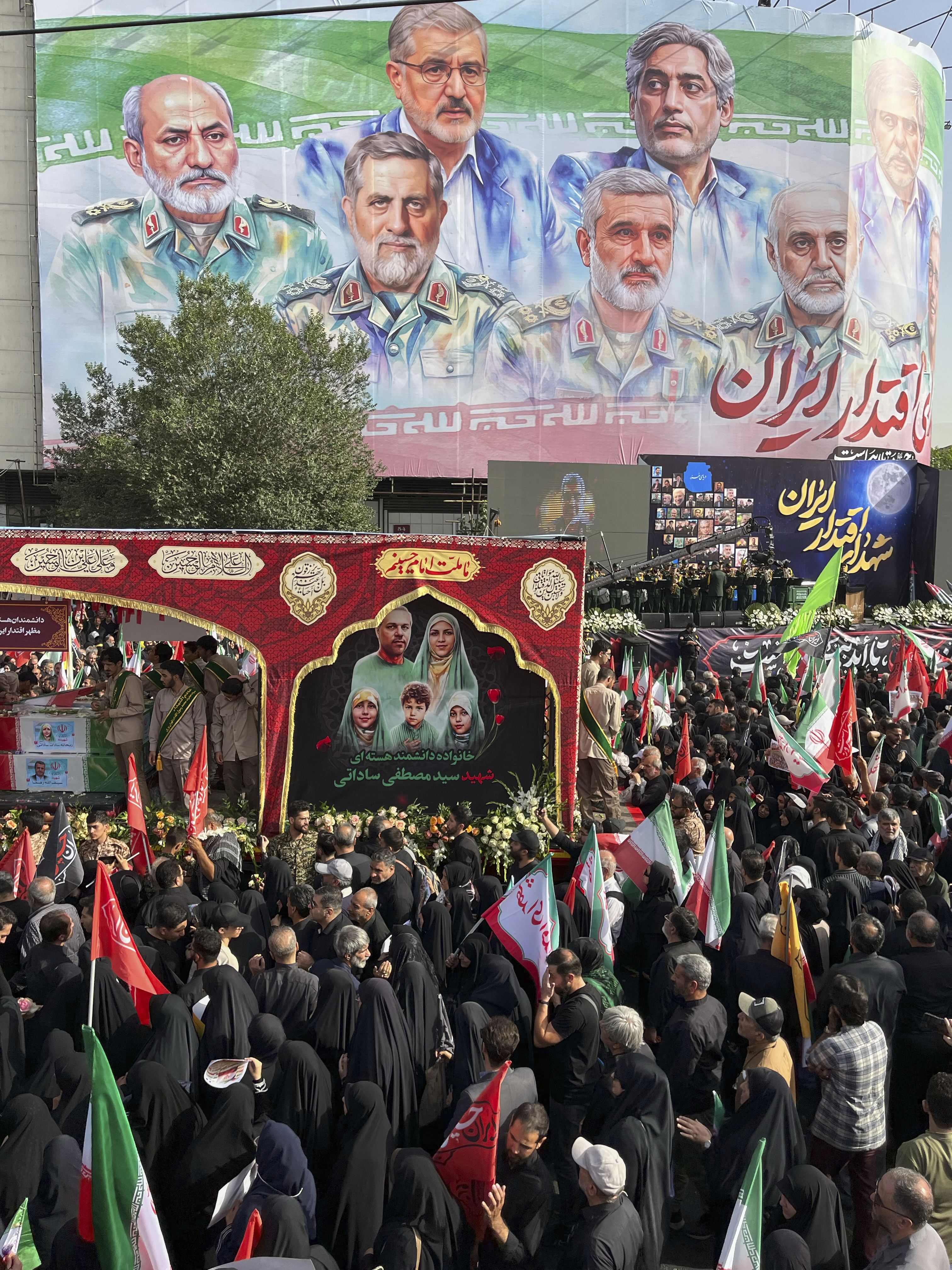 People mourn over the flag-draped coffins of Iranian army generals, nuclear scientists and their family members who were killed in Israeli strikes, during a funeral ceremony in Tehran. Iran, Saturday, June 28, 2025. (AP Photo/Vahid Salemi)