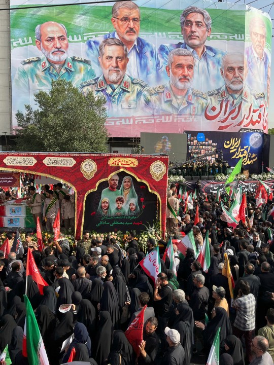 People mourn over the flag-draped coffins of Iranian army generals, nuclear scientists and their family members who were killed in Israeli strikes, during a funeral ceremony in Tehran. Iran, Saturday, June 28, 2025. (AP Photo/Vahid Salemi)