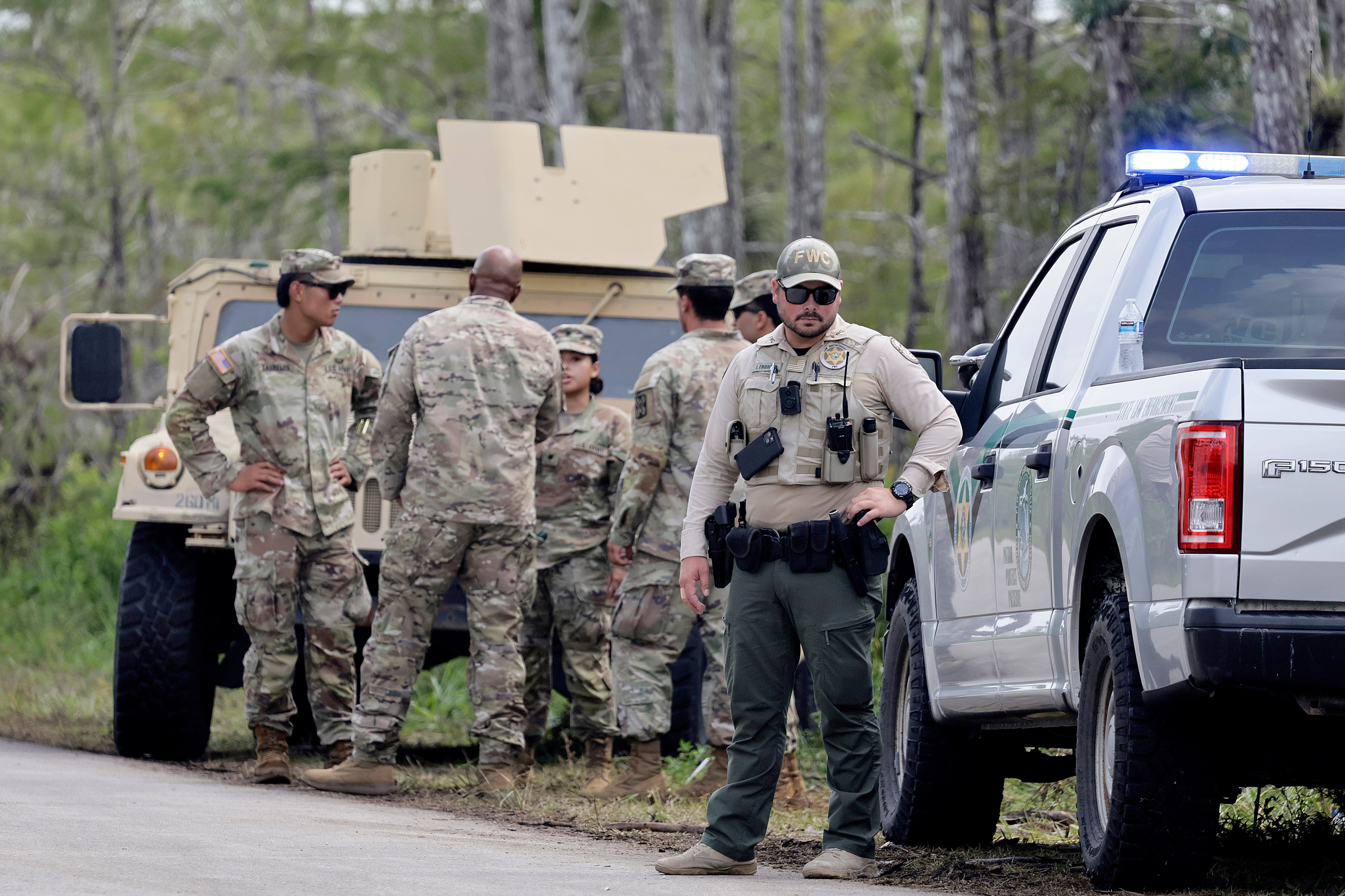 Law enforcement gather at the the gate during a protest at the Dade-Collier Training and Transition Airport on Tamiami Trail E, Ochopee, on Saturday, June 28, 2025. (Mike Stocker/South Florida Sun-Sentinel via AP)