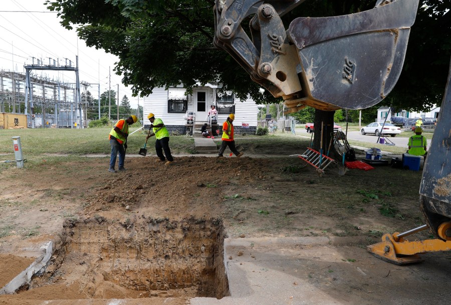 FILE - Workers back fill a hole used to replace lead pipe with copper water supply lines to a home in Flint, Mich., July 20, 2018. (AP Photo/Paul Sancya, File)