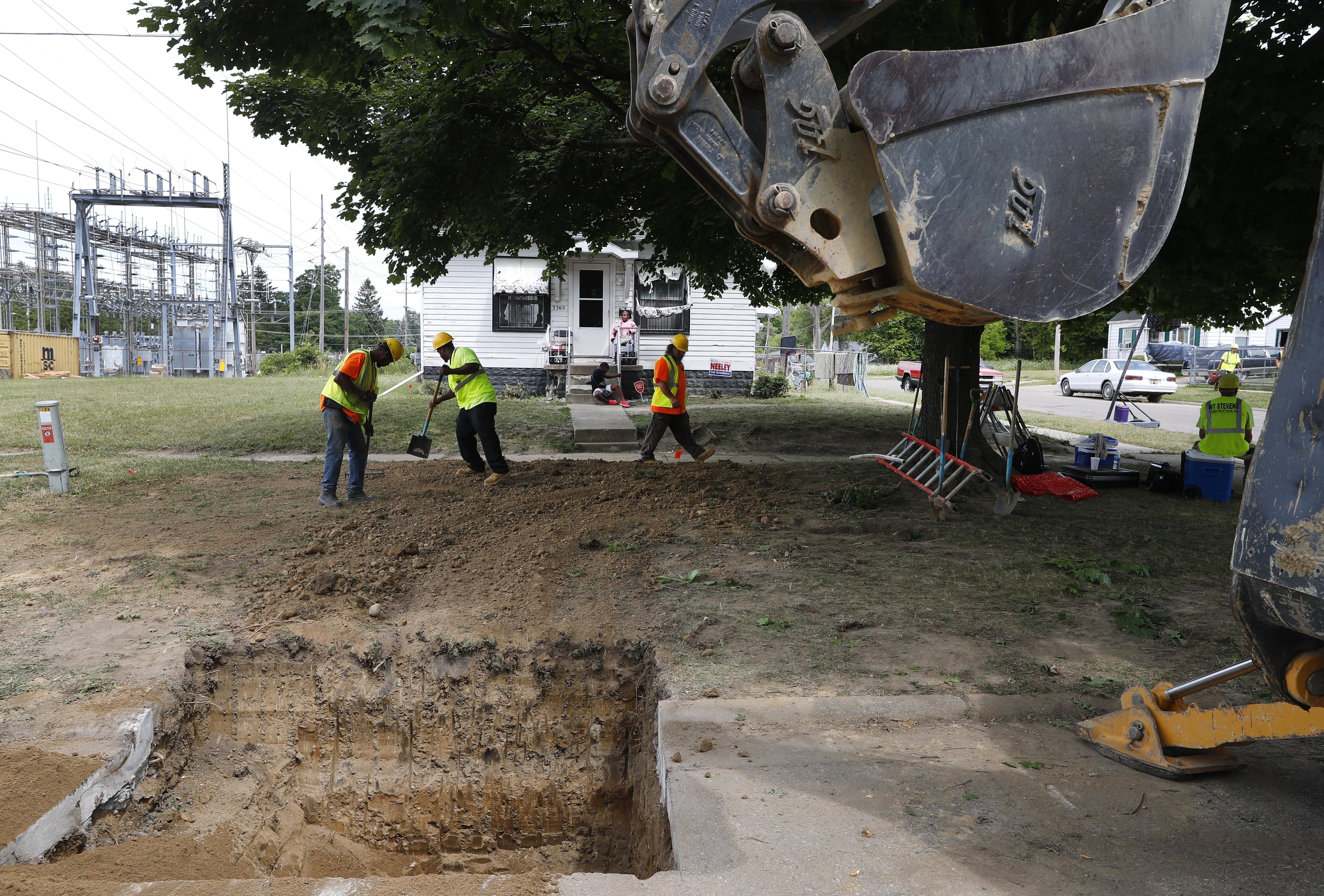 FILE - Workers back fill a hole used to replace lead pipe with copper water supply lines to a home in Flint, Mich., July 20, 2018. (AP Photo/Paul Sancya, File)