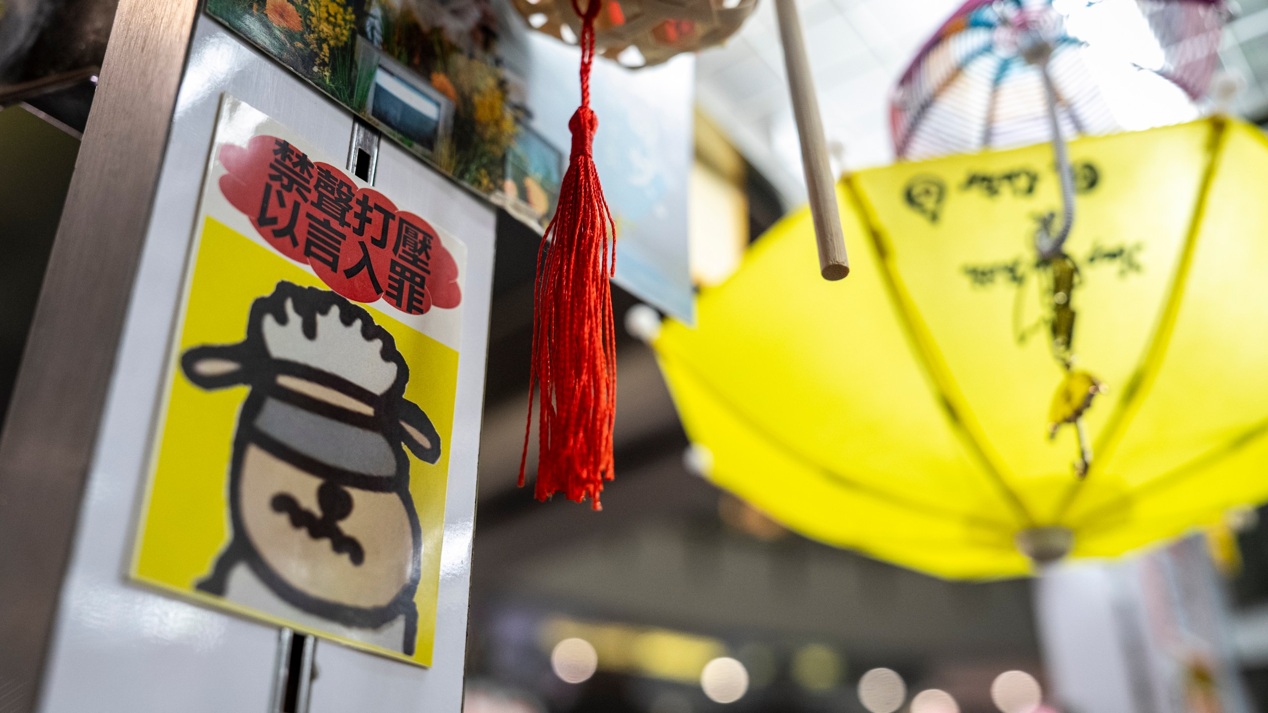 A sticker reads, "Silencing dissent and criminalizing speech," displayed at Chan Kim Kam's stall selling incense and essential oils in Hong Kong, Friday, June 20, 2025. (AP Photo/Chan Long Hei)