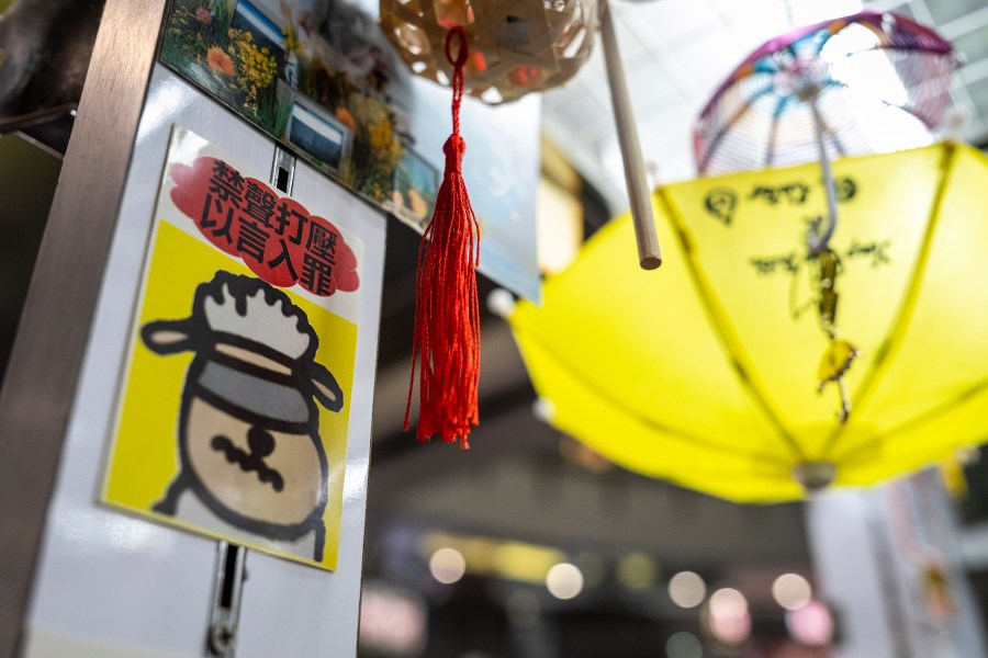 A sticker reads, "Silencing dissent and criminalizing speech," displayed at Chan Kim Kam's stall selling incense and essential oils in Hong Kong, Friday, June 20, 2025. (AP Photo/Chan Long Hei)